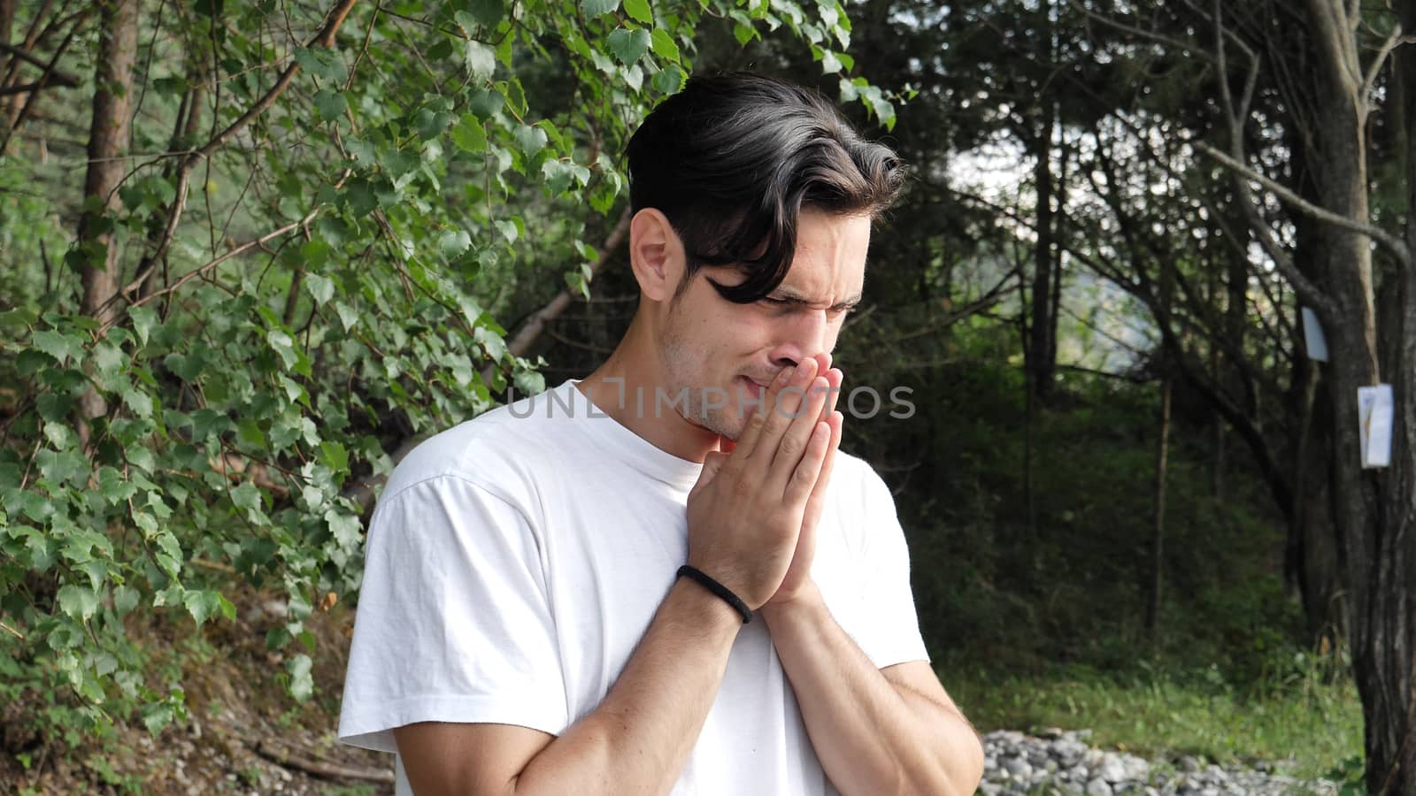 Young handsome man standing in nature, sad, worried or upset, crying