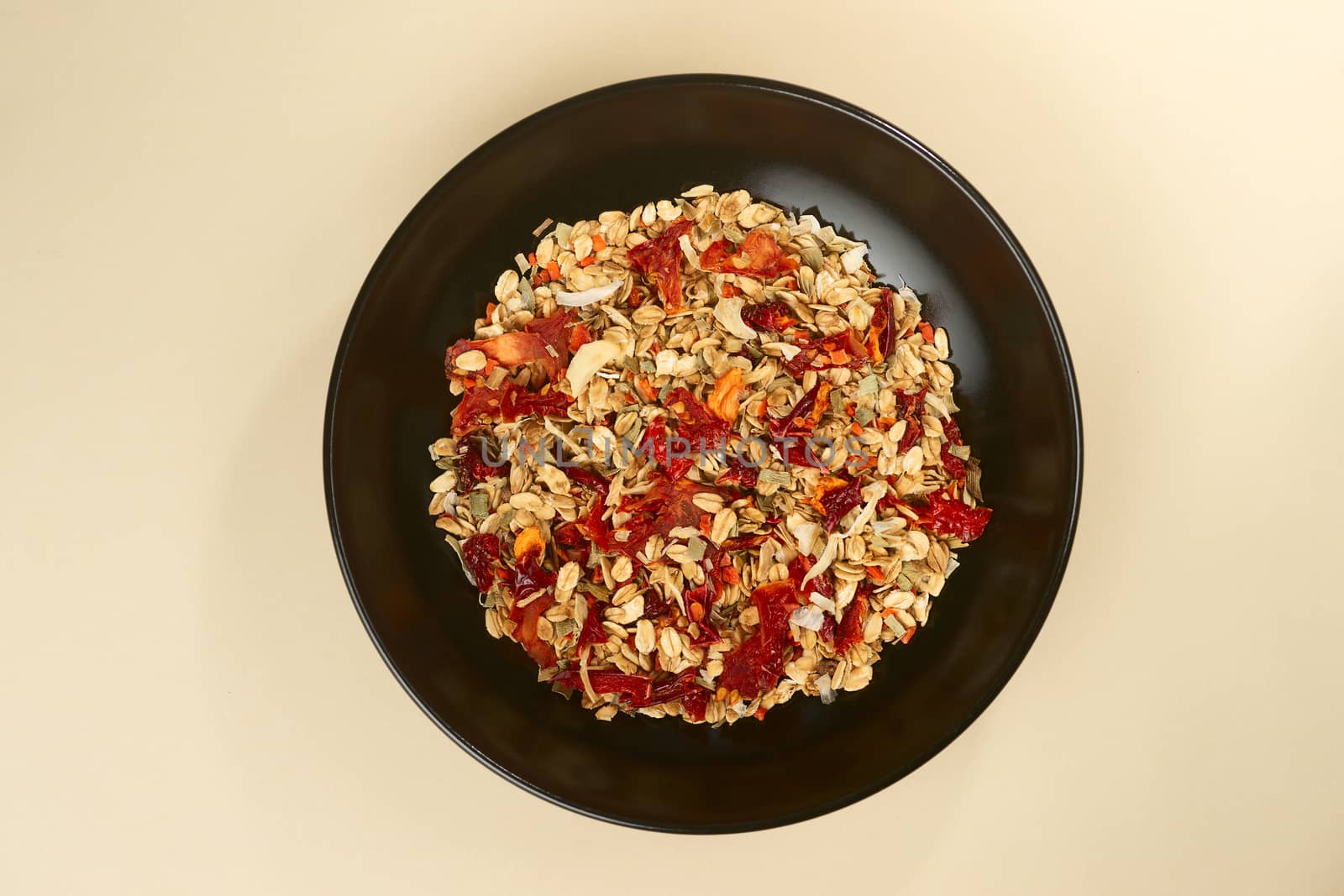 A tasty salt granola with pepper in black bowl on baige bakground. Concept of nutrient and healty breakfast or meal and vegan or vegetarian food.