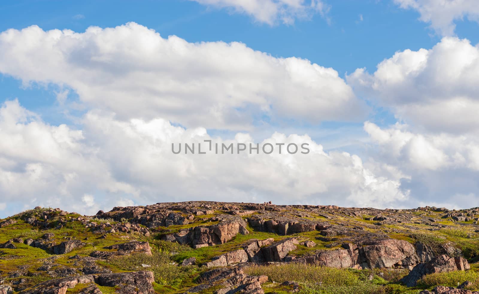 Fluffy white clouds move smoothly over rocks, hills and grasses by laihio