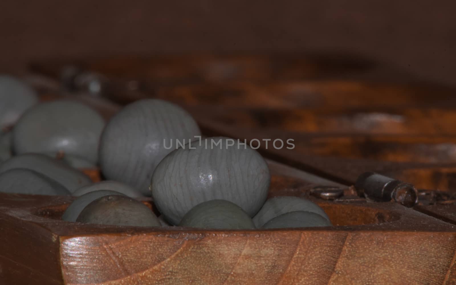 Closeup of a wooden mancala game with grey stones