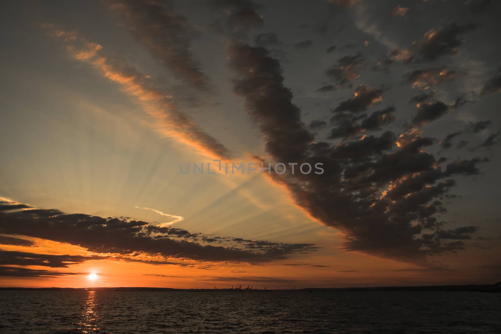 Beautiful sunirse over the horizon with sunrays and clouds by the ocean