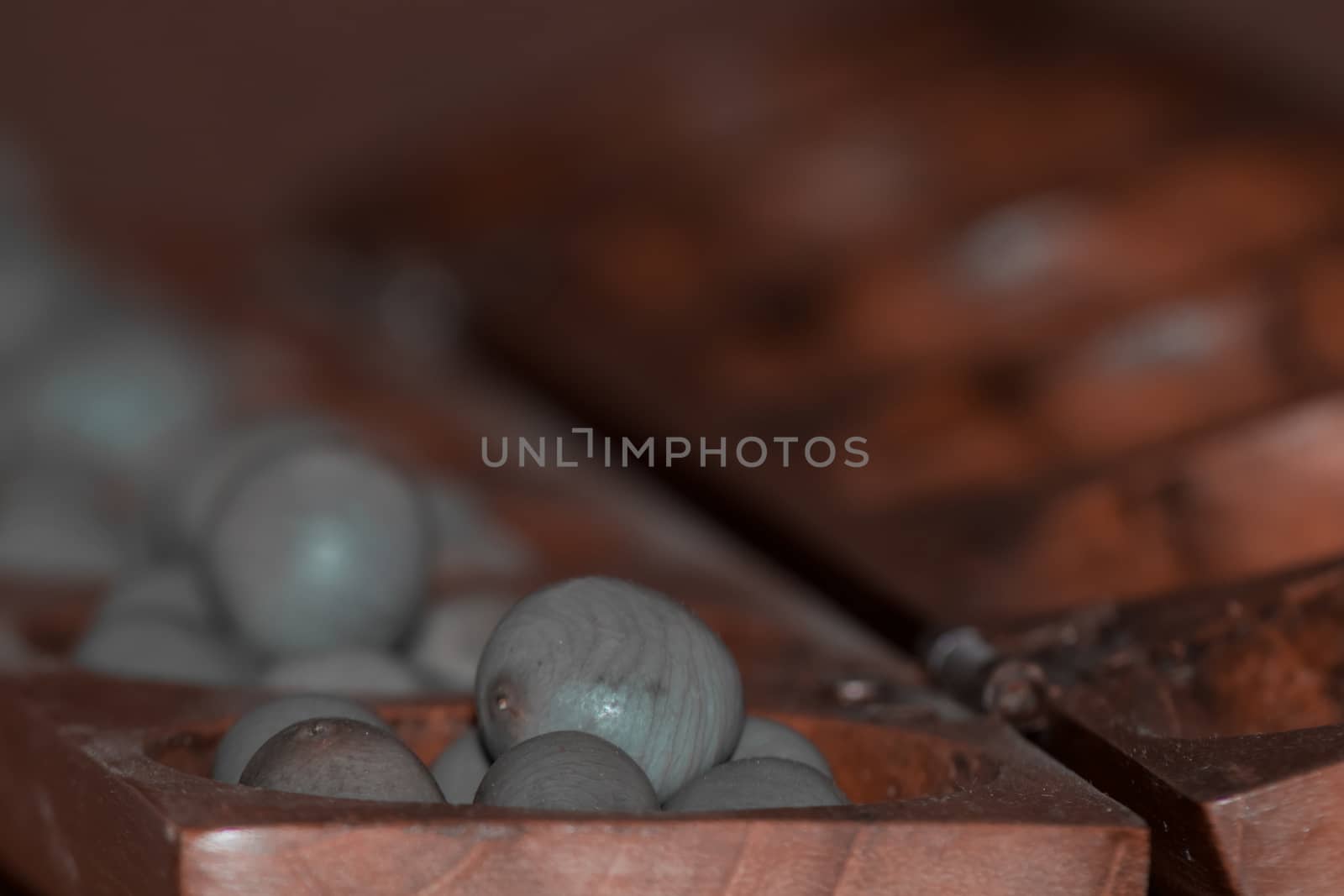 Closeup of a wooden mancala game with grey stones