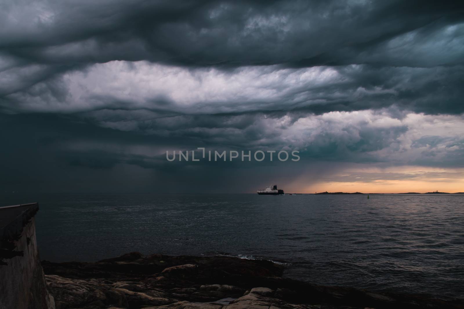 A cargo ship underneath stormy clouds during sunset