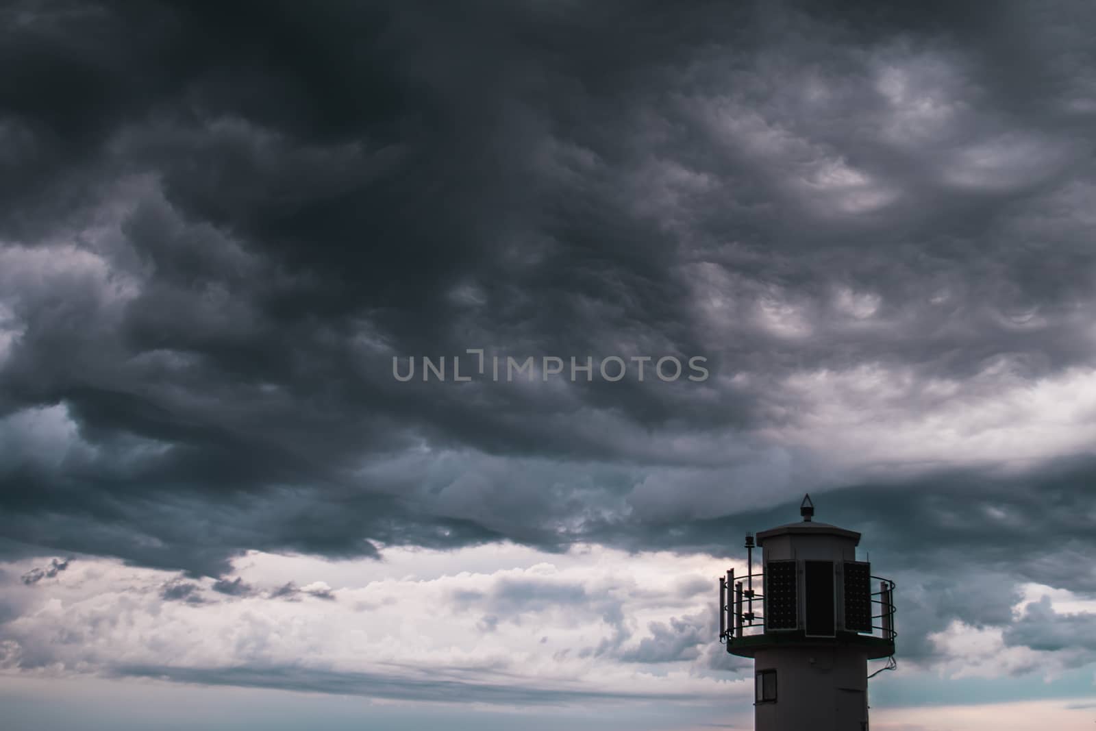 The silhouette of a lighthuse infront of a stormy cloudscape