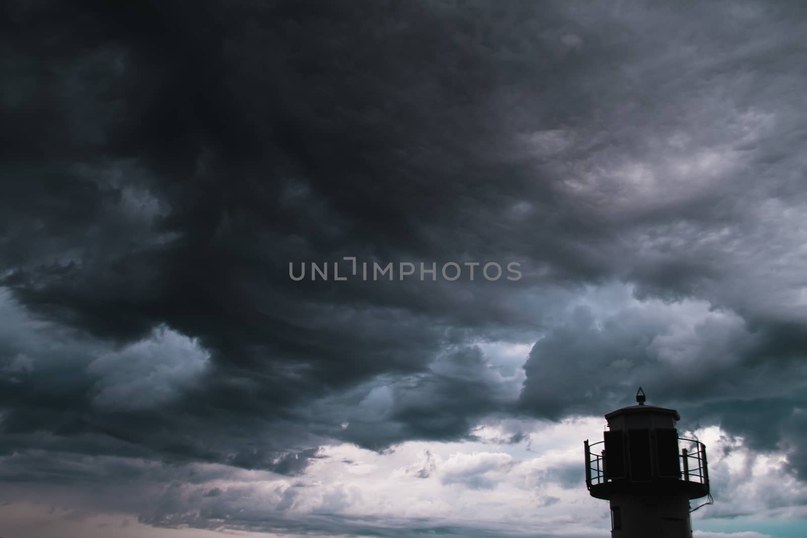 The silhouette of a lighthuse infront of a stormy cloudscape