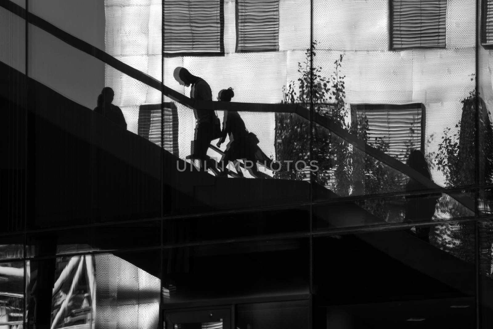 Reflection of people walking up and down some stairs in the city