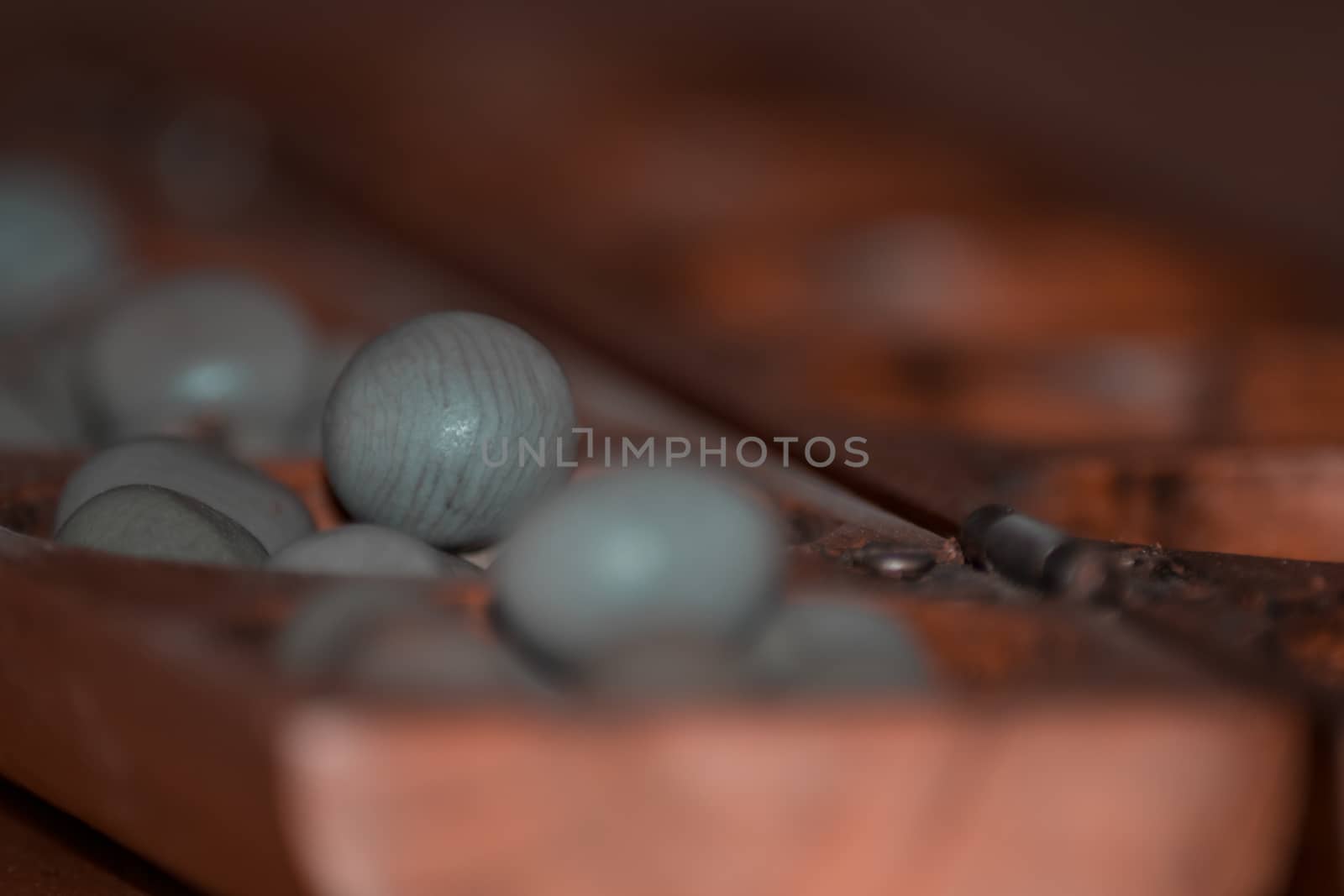 Closeup of a wooden mancala game with grey stones