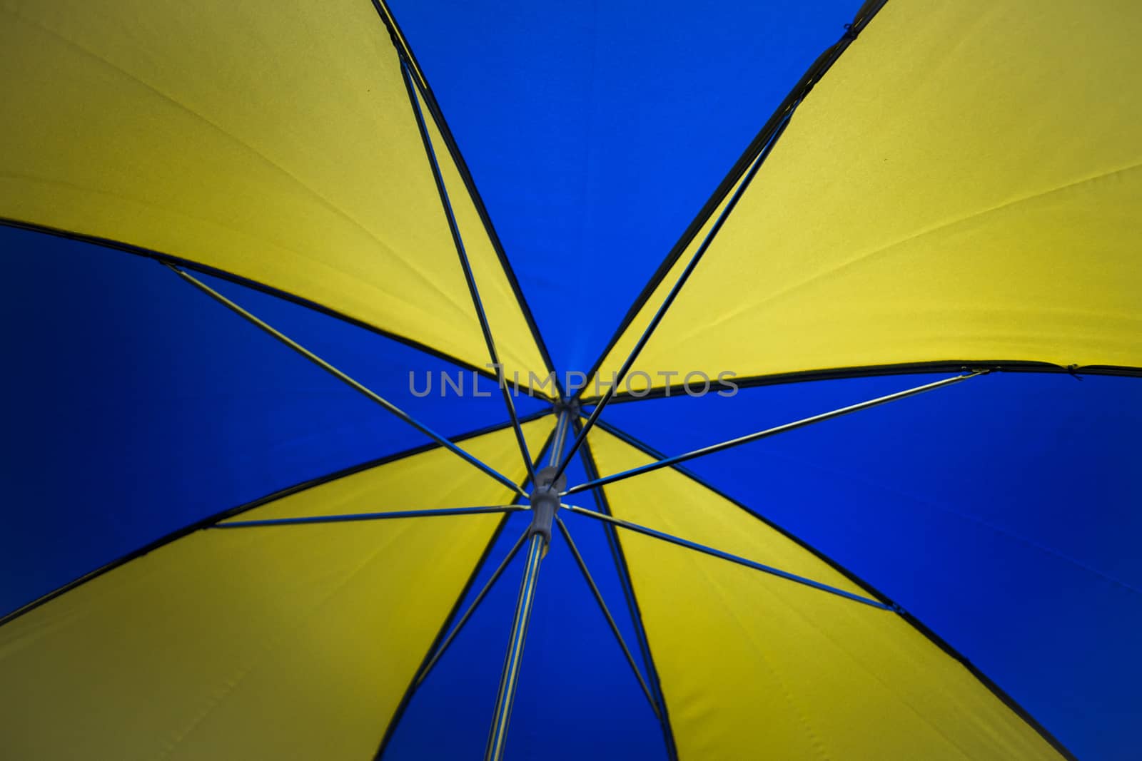 Underneath a blue and yellow umbrella