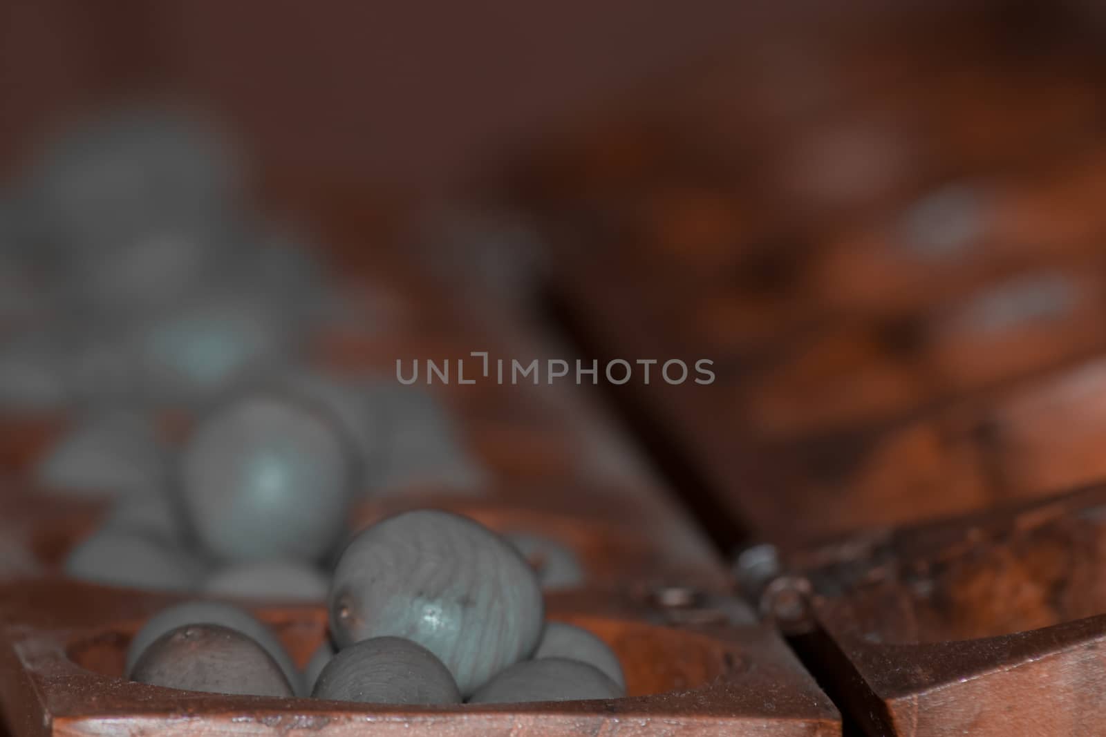 Closeup of a wooden mancala game with grey stones