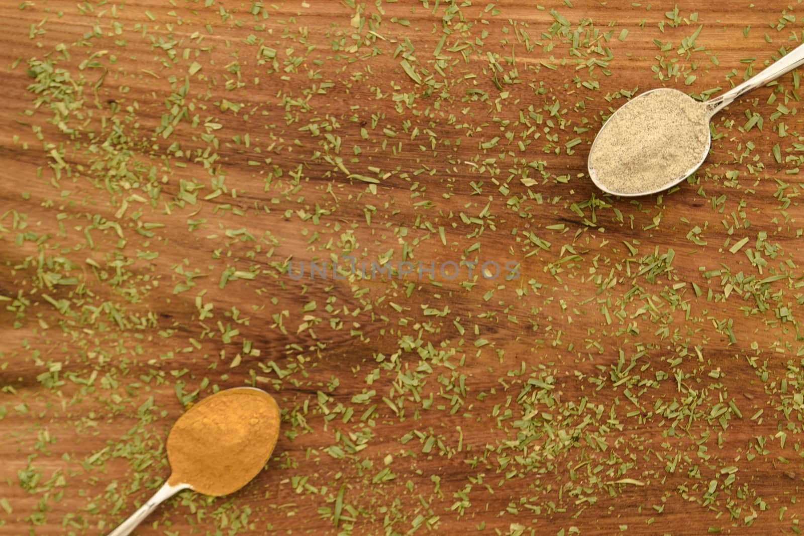 Various colorful spices arranged on spoons  with wooden background