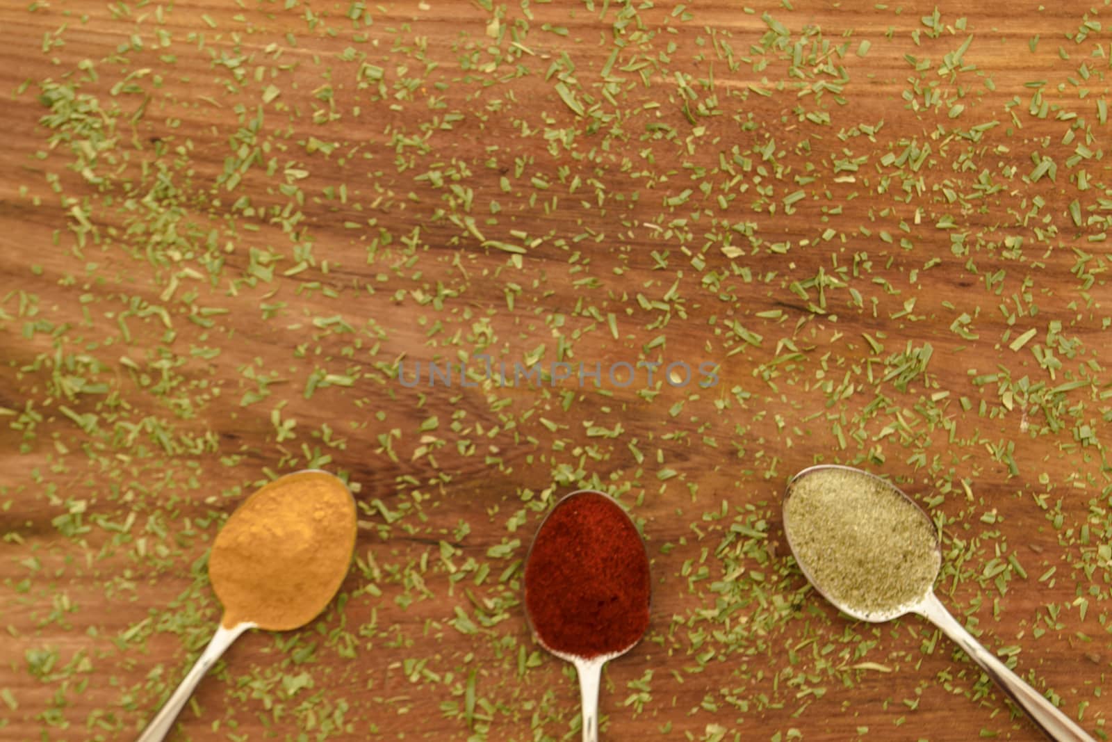 Various colorful spices arranged on spoons  with wooden background