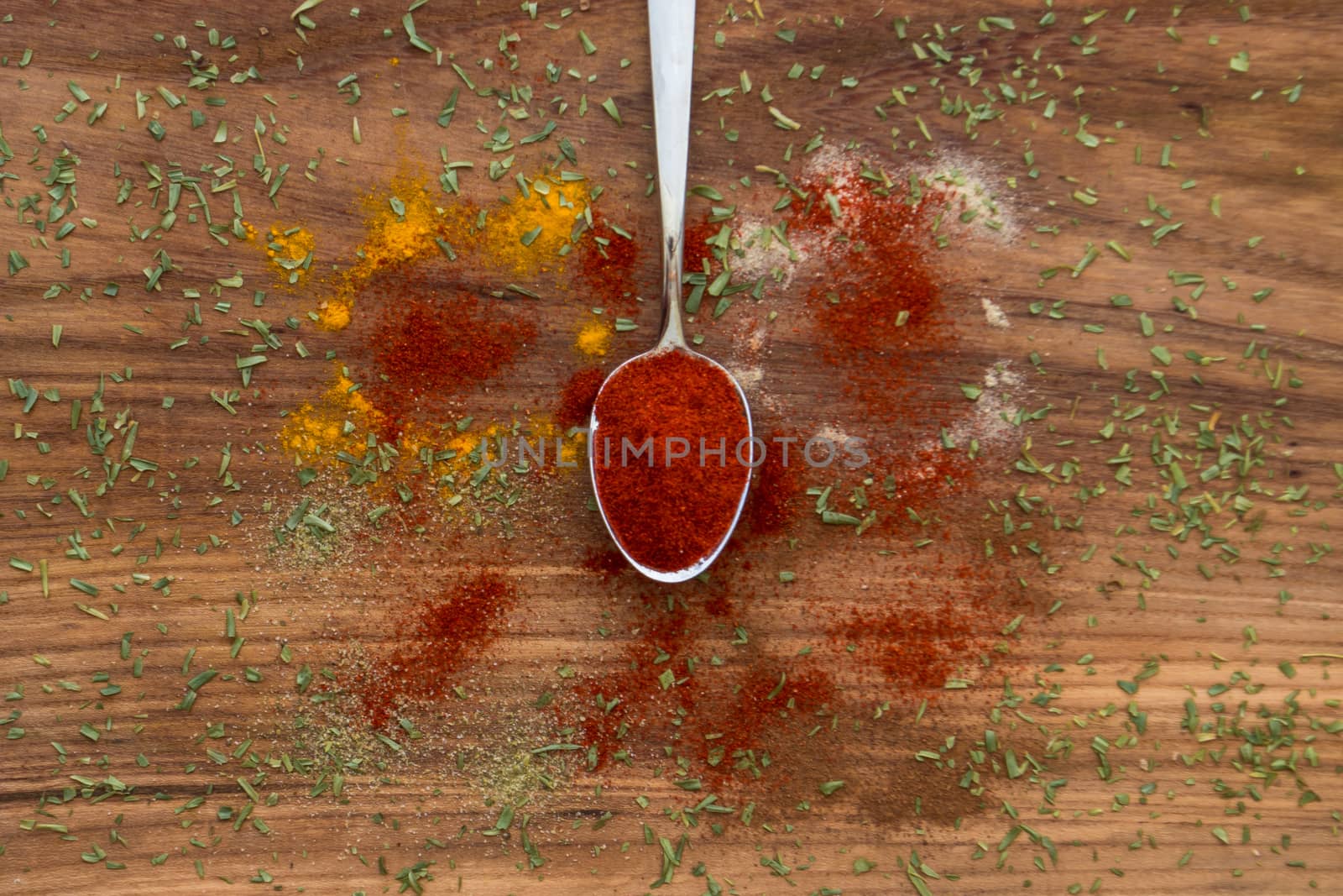 Red paprika spice on a spoon with wooden background