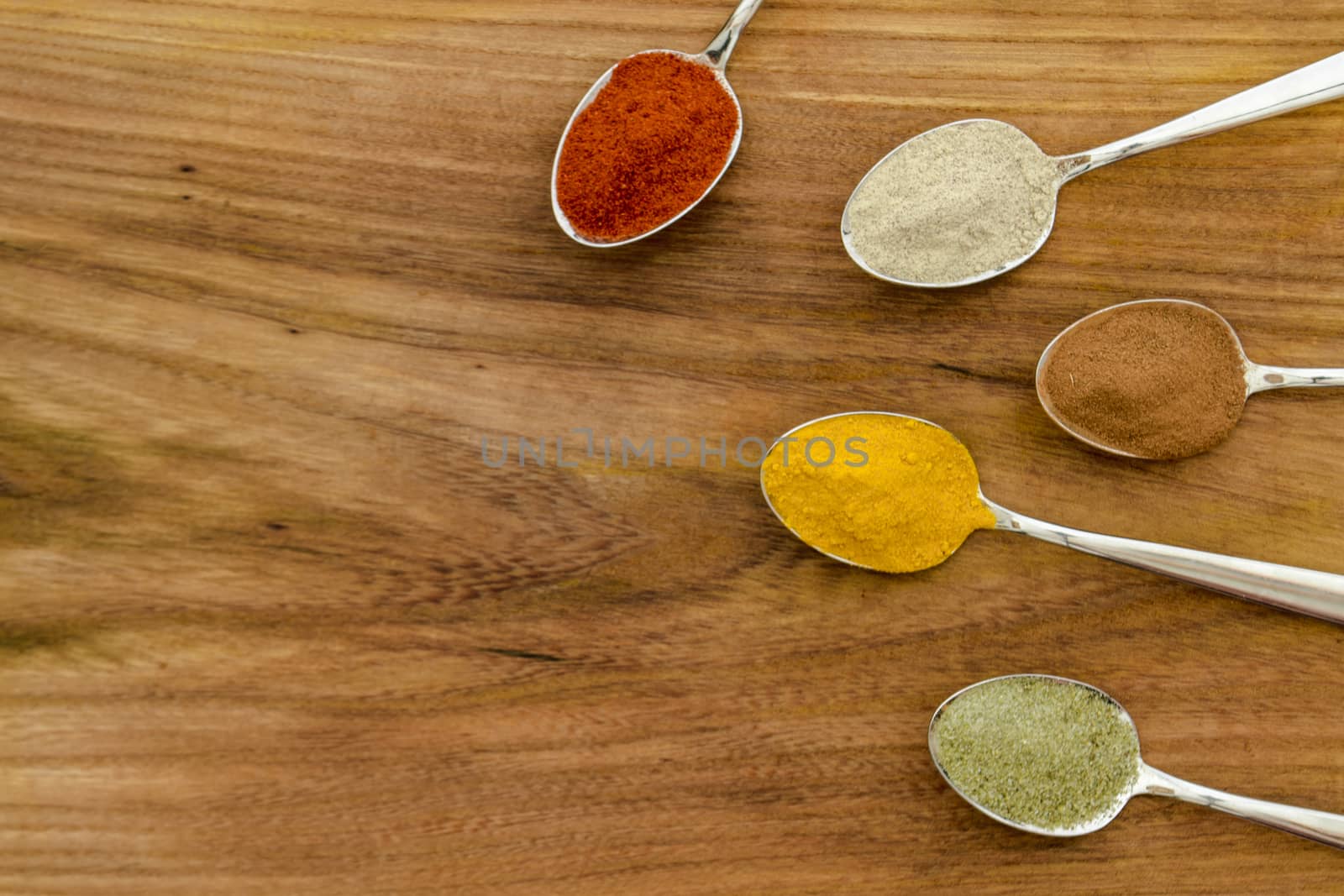 Various colorful spices arranged on spoons  by arvidnorberg