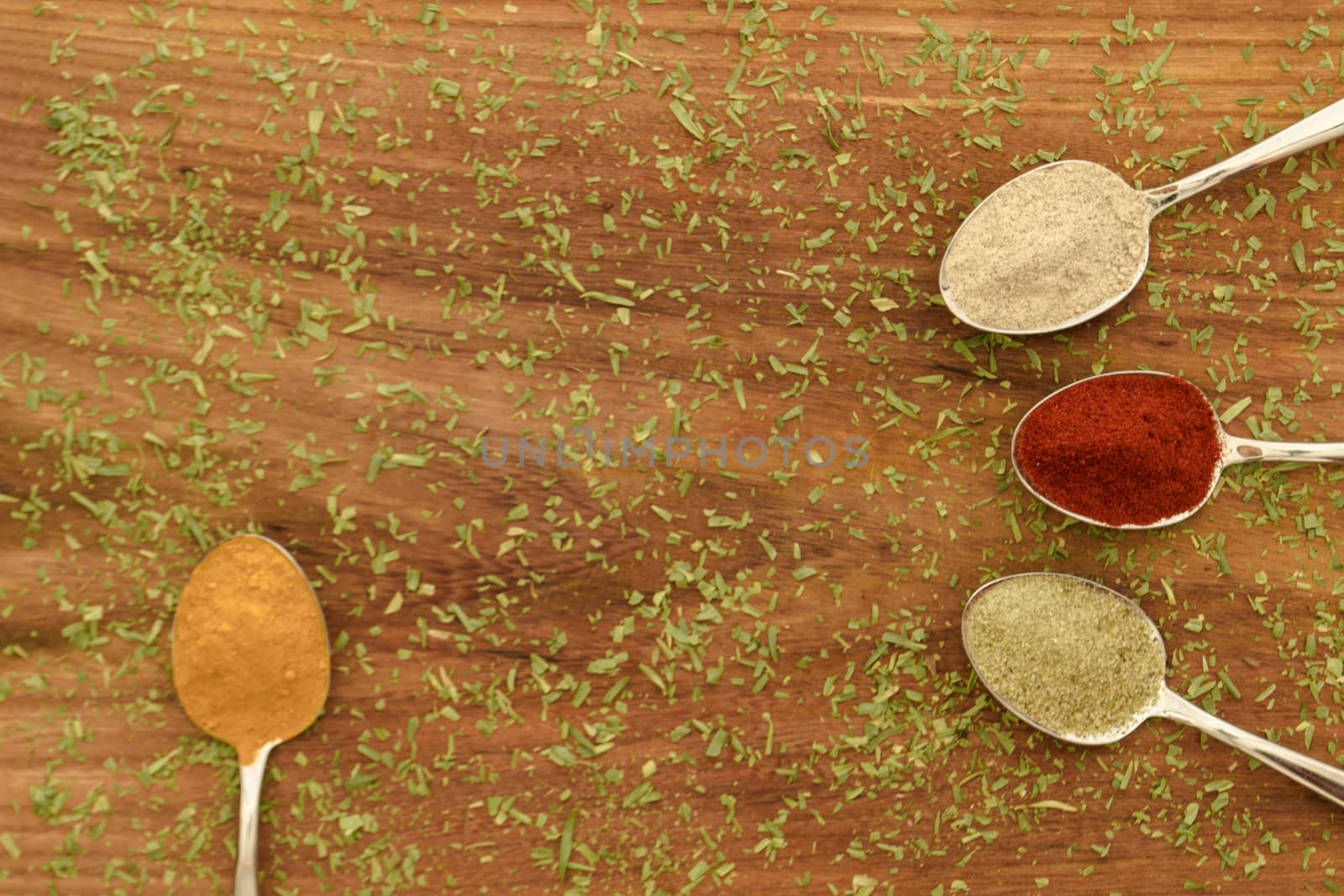 Various colorful spices arranged on spoons  with wooden background