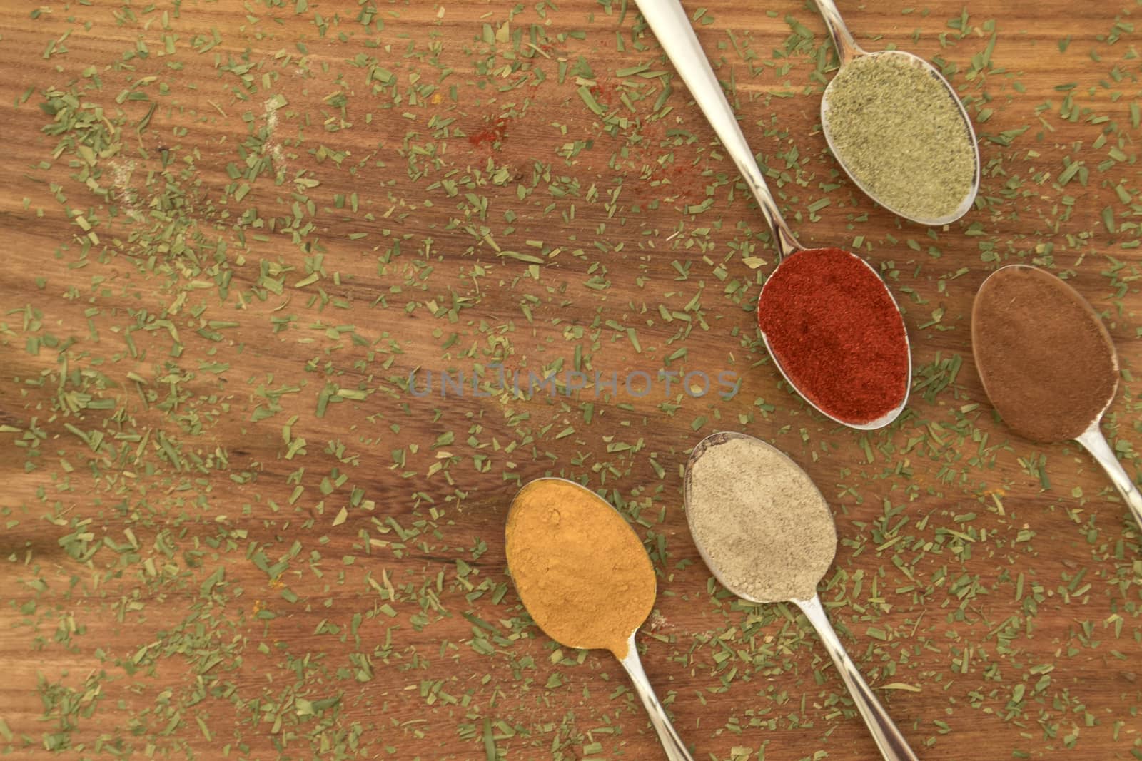 Various colorful spices arranged on spoons  with wooden background