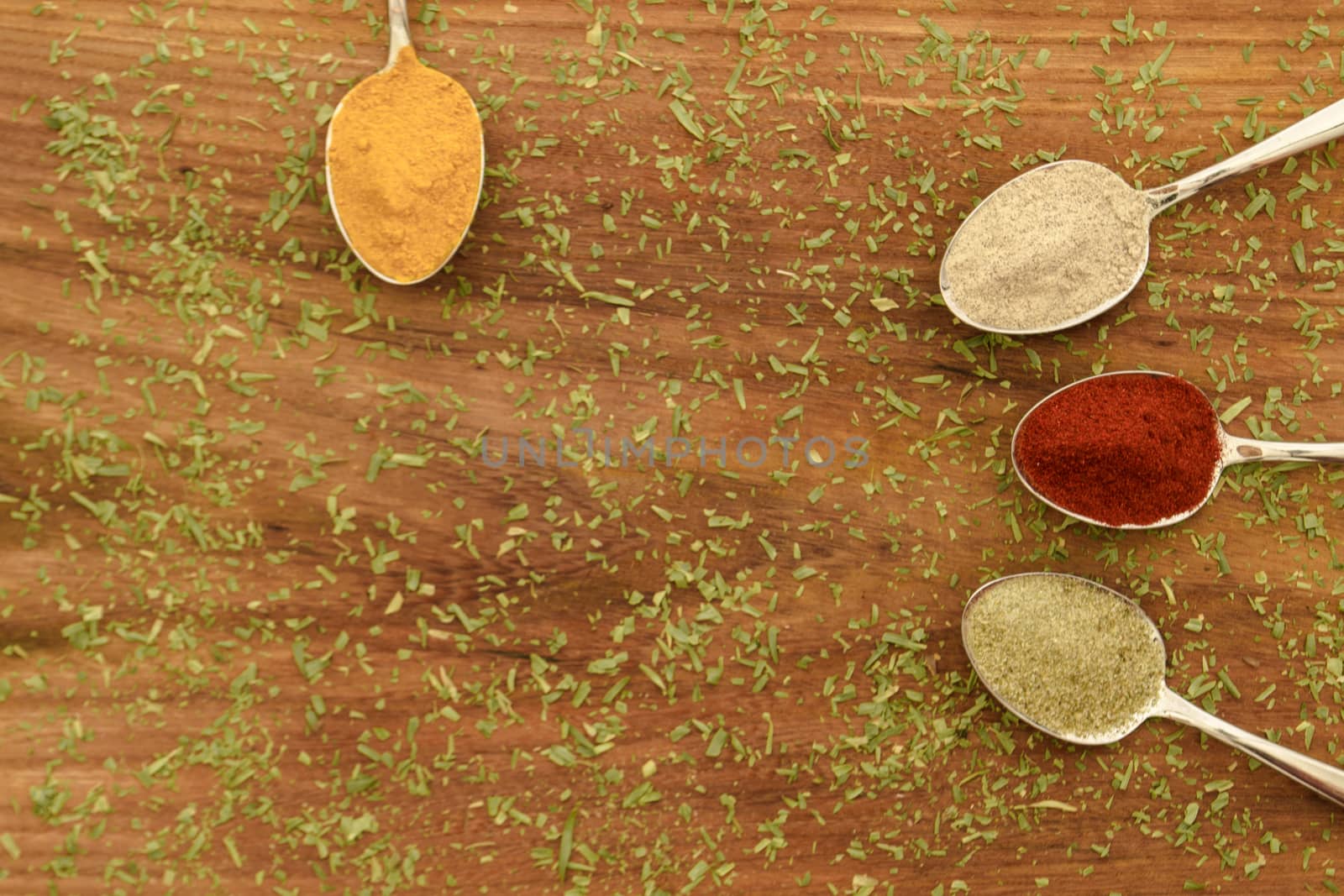 Various colorful spices arranged on spoons  with wooden background