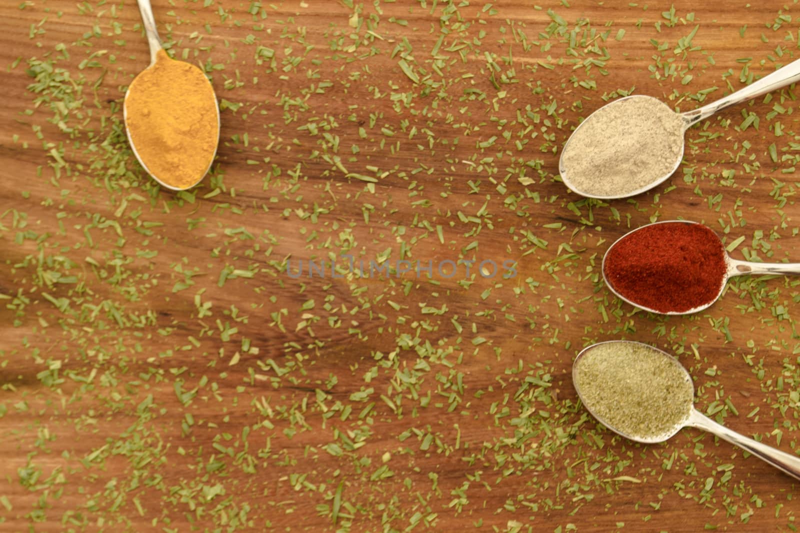 Various colorful spices arranged on spoons  with wooden background