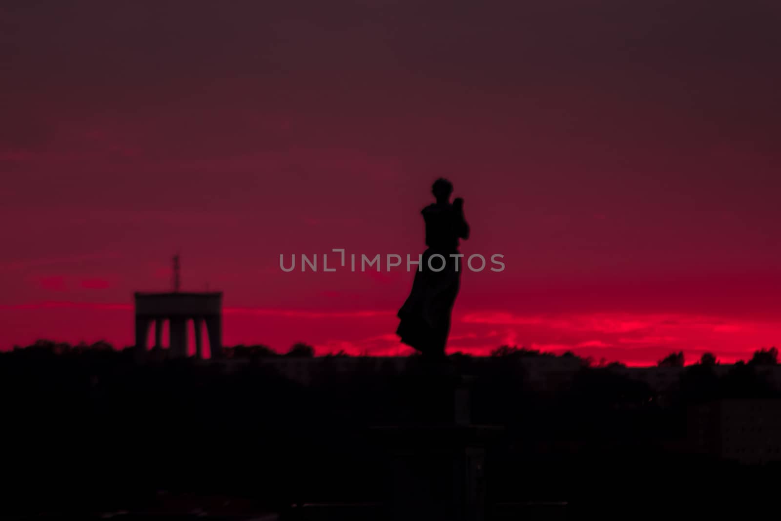 Silhouette of a woman and an arch during a pink sunset