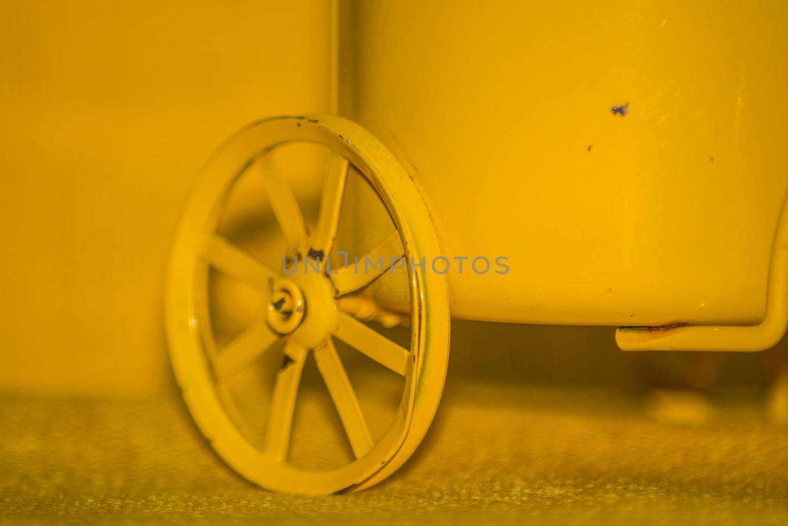 Closeup of a yellow toy wheel infront of a yellow background