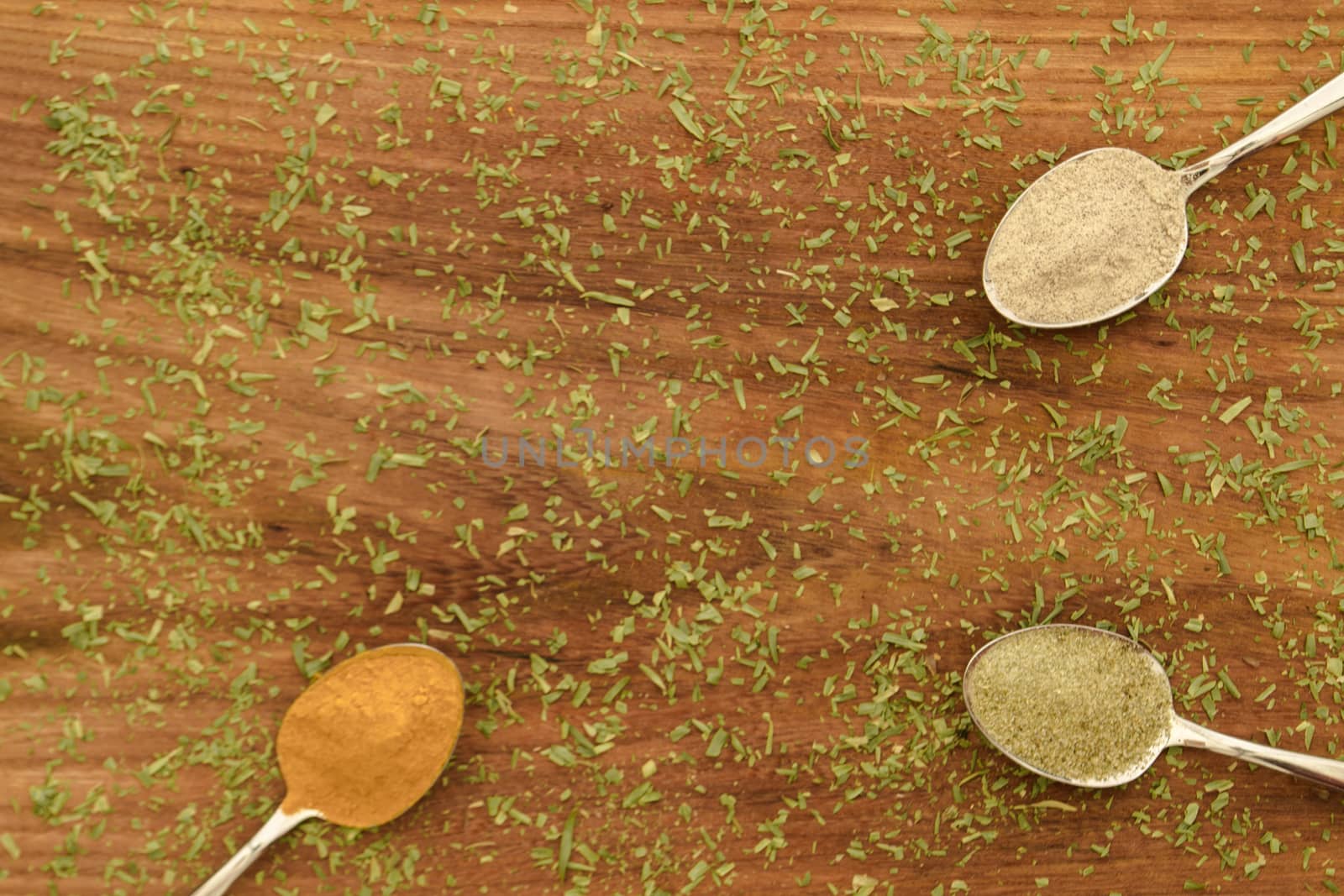 Various colorful spices arranged on spoons  with wooden background