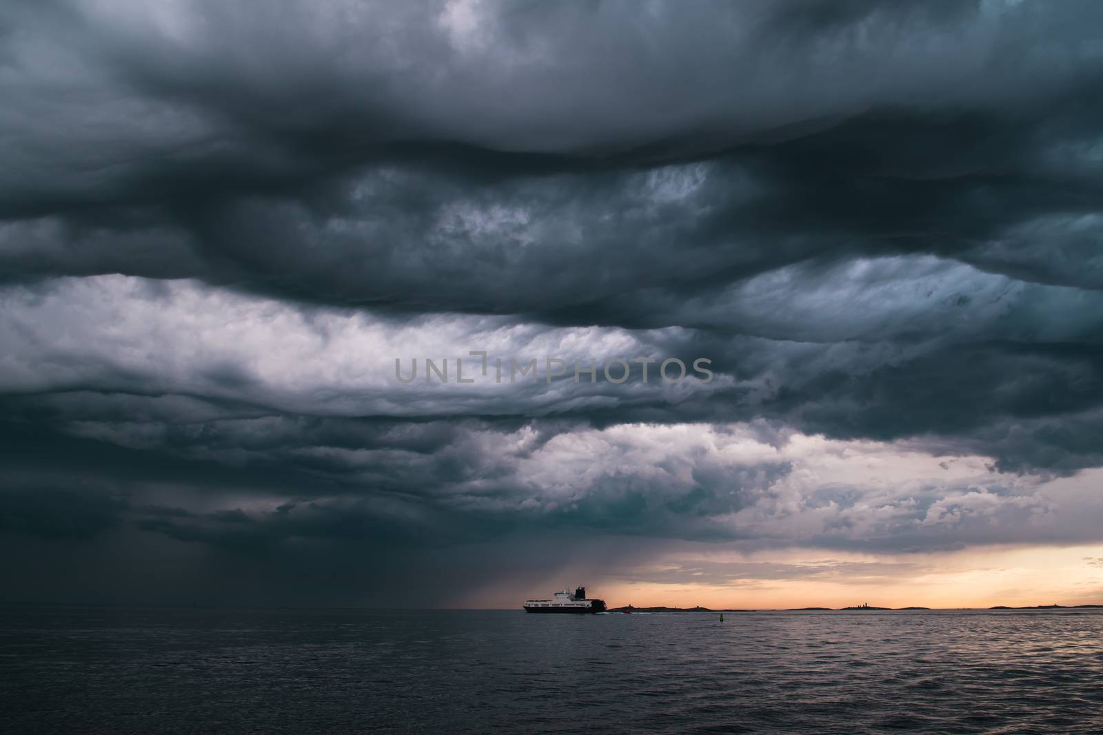 A cargo ship underneath stormy clouds during sunset