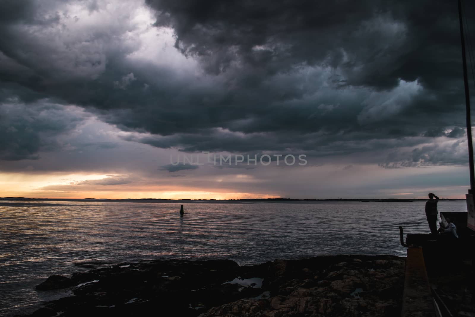 A person by the shore during stormy cloudscape by arvidnorberg