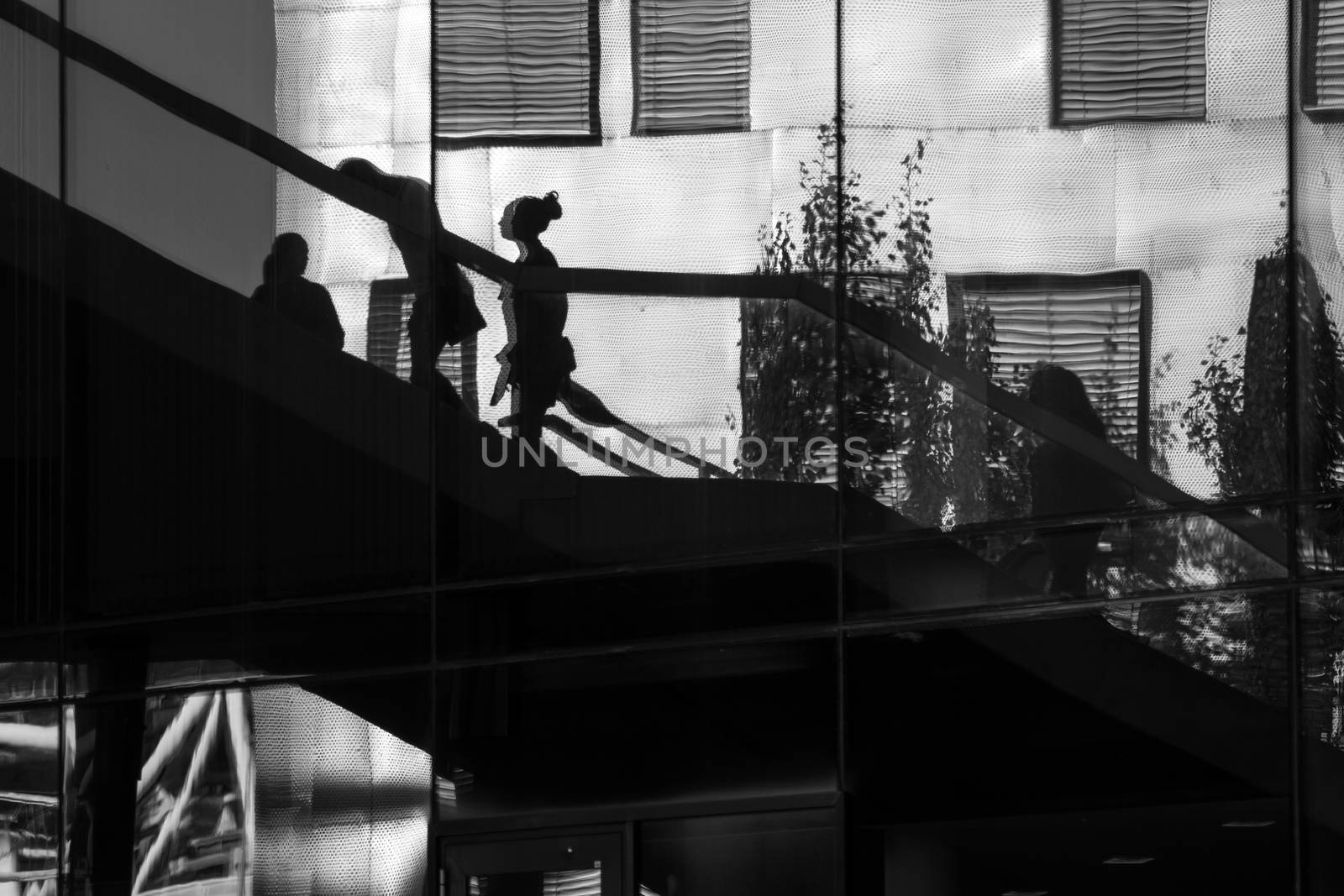 Reflection of people walking up and down some stairs in the city