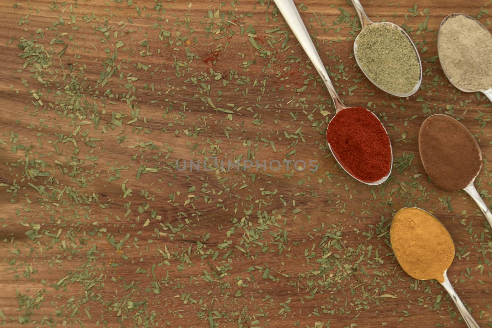 Various colorful spices arranged on spoons  with wooden background