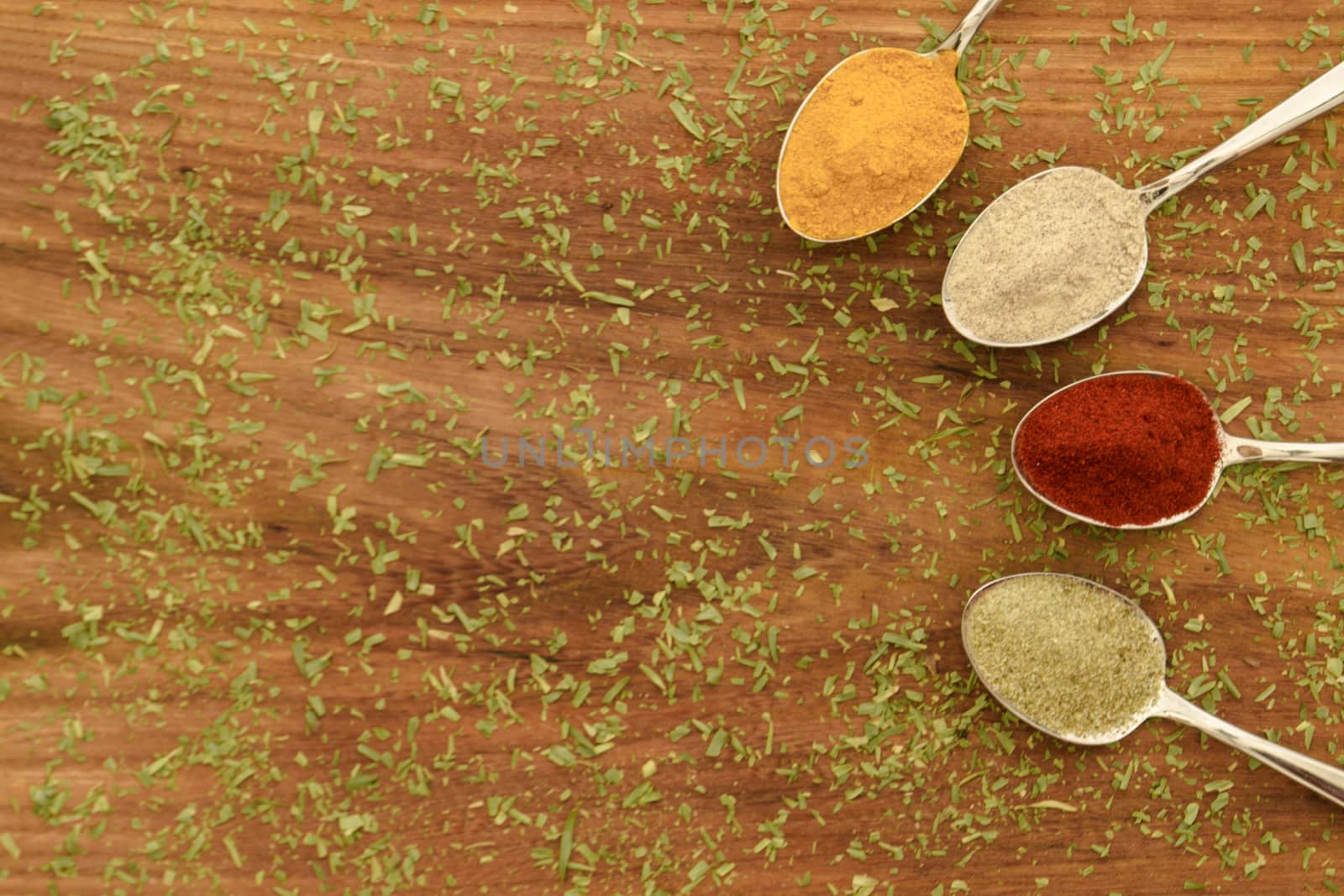 Various colorful spices arranged on spoons  with wooden background