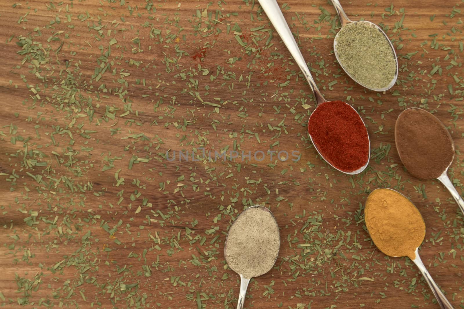 Various colorful spices arranged on spoons  with wooden background