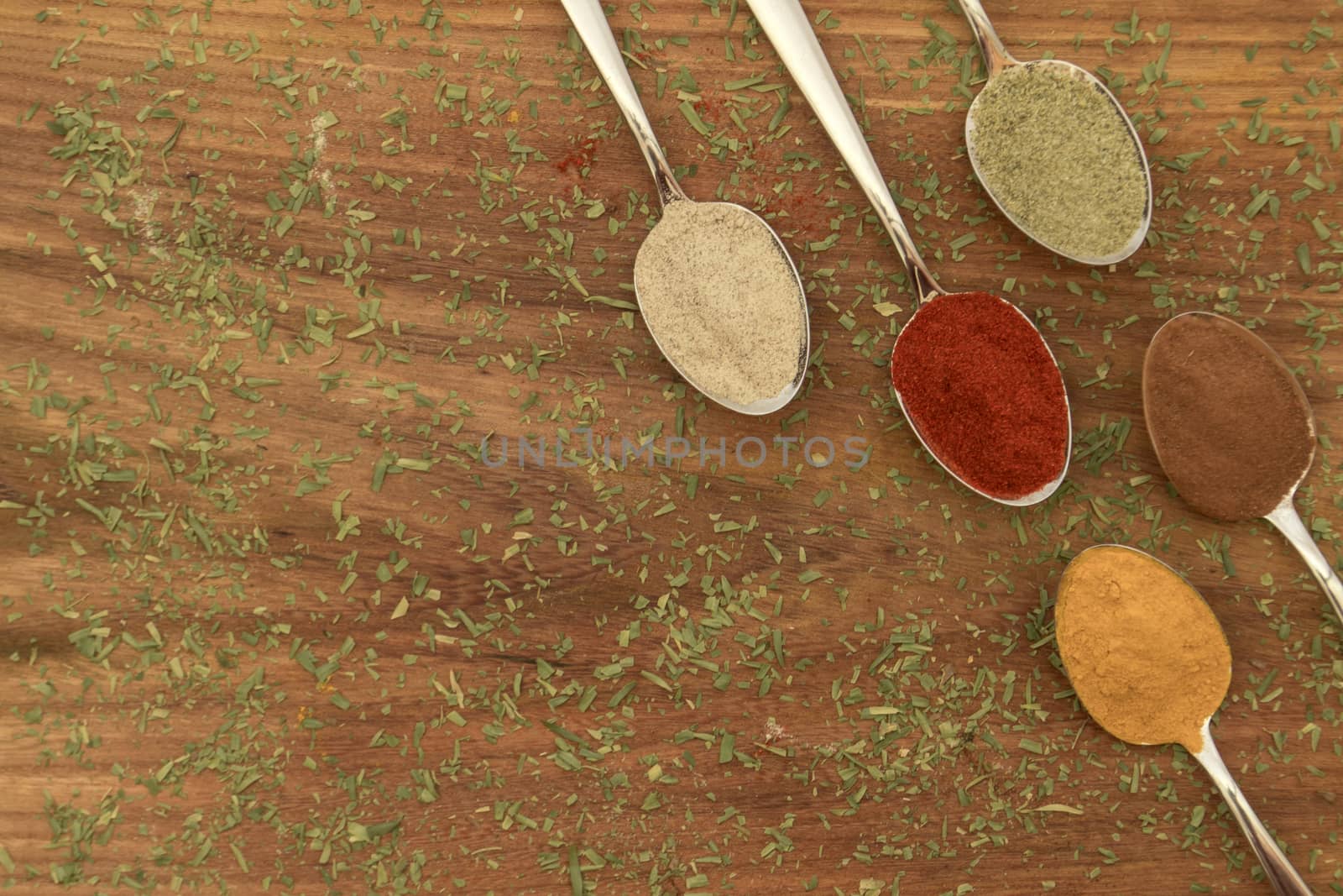 Various colorful spices arranged on spoons  with wooden background