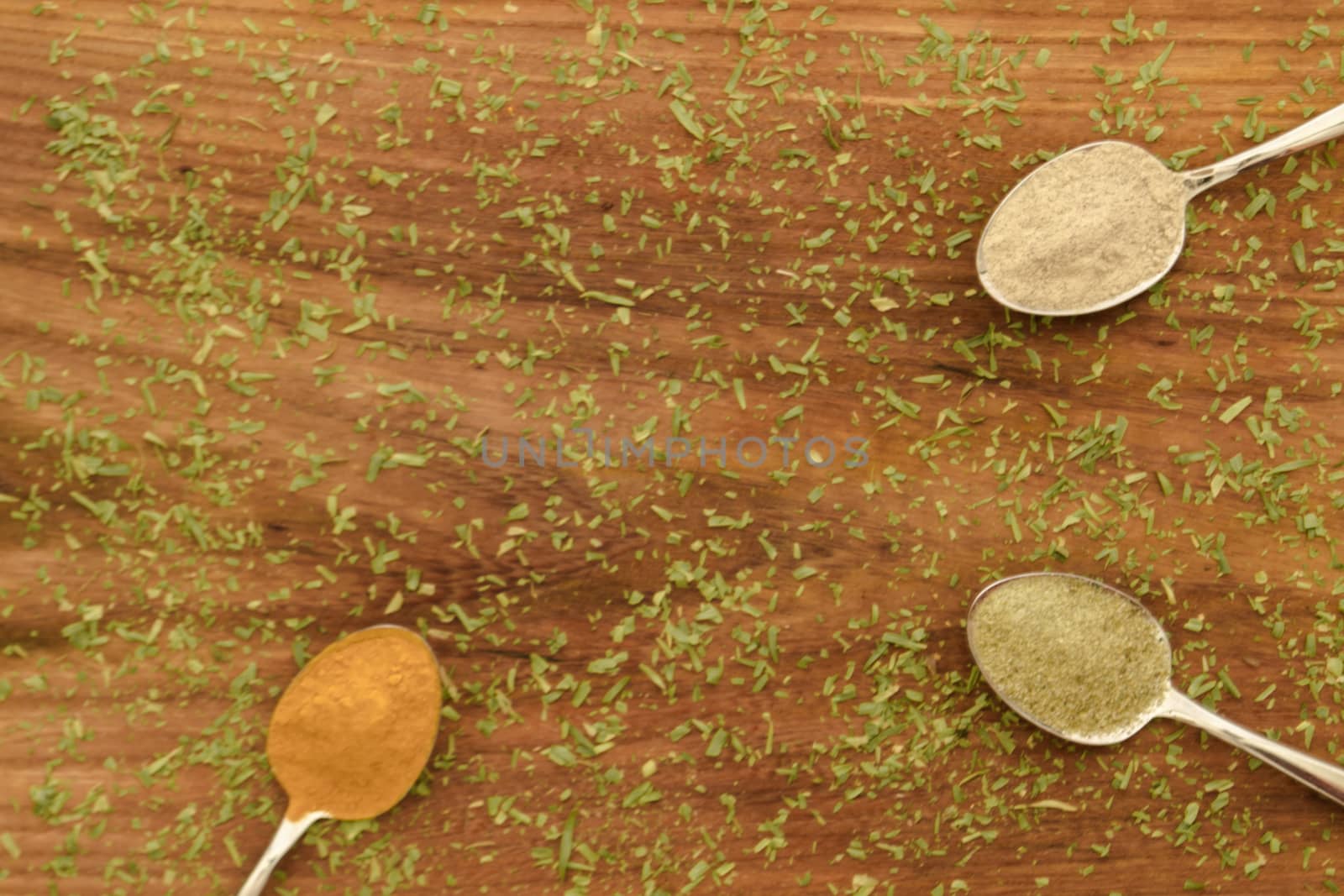 Various colorful spices arranged on spoons  with wooden background