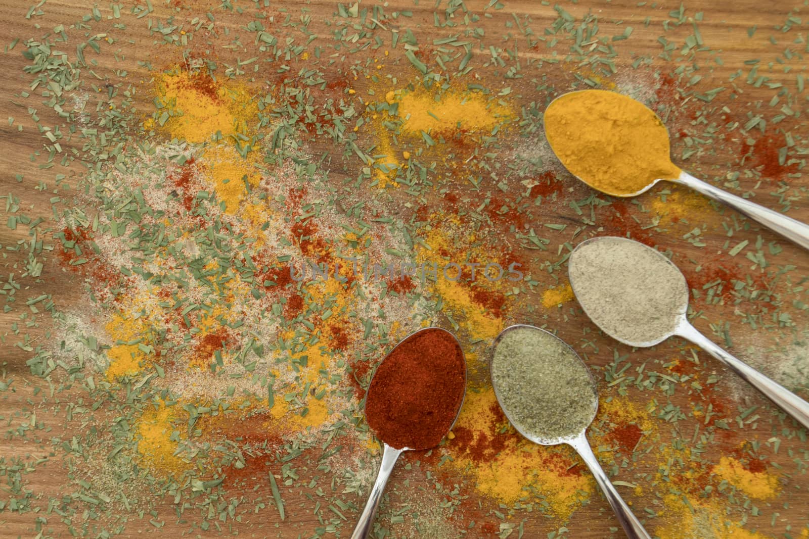 Various colorful spices arranged on spoons  with wooden background