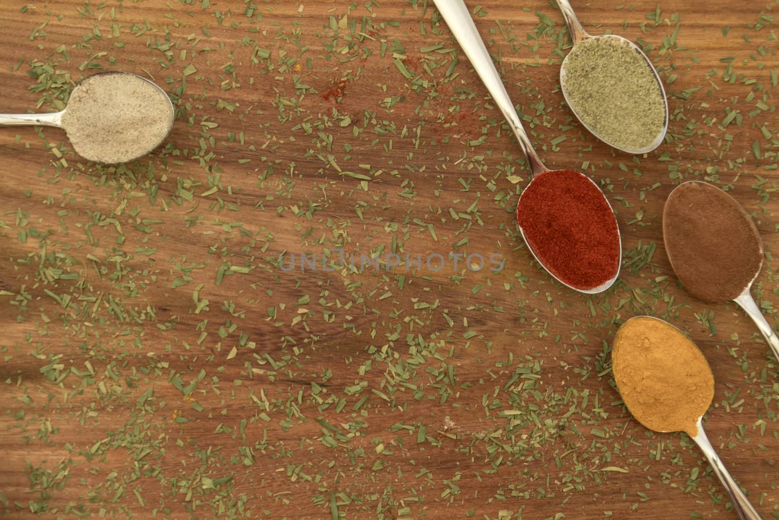 Various colorful spices arranged on spoons  with wooden background