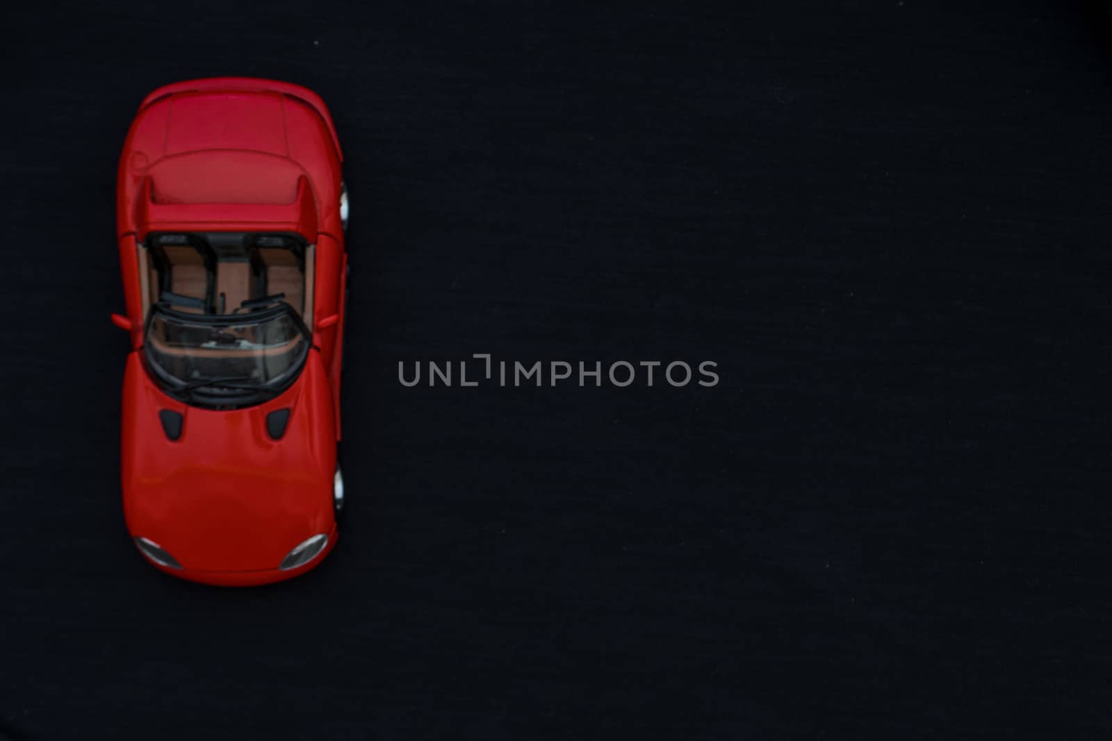 Flat lay of a red toy car with black background