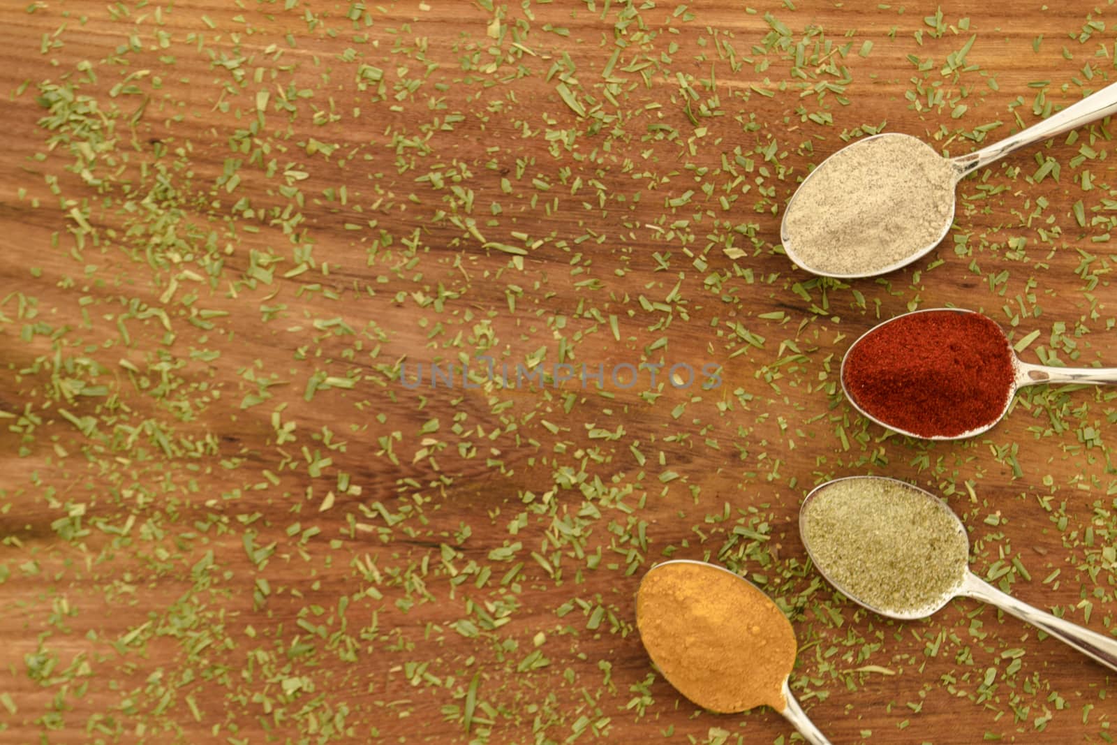 Various colorful spices arranged on spoons  with wooden background