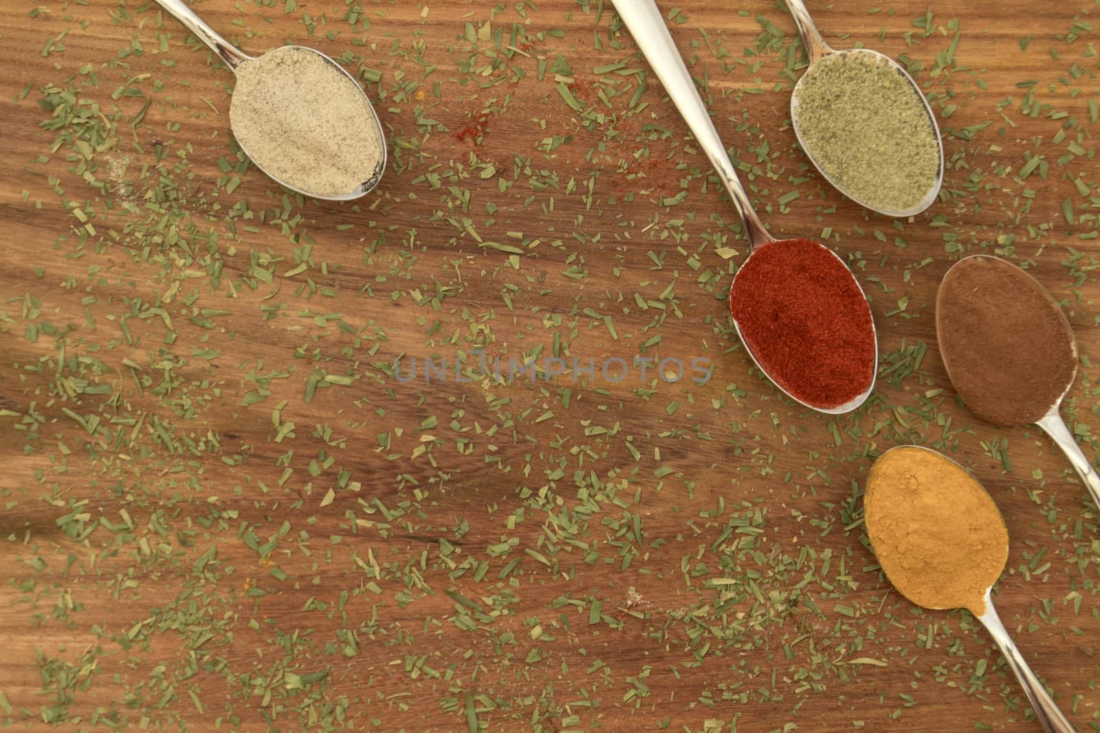 Various colorful spices arranged on spoons  with wooden background