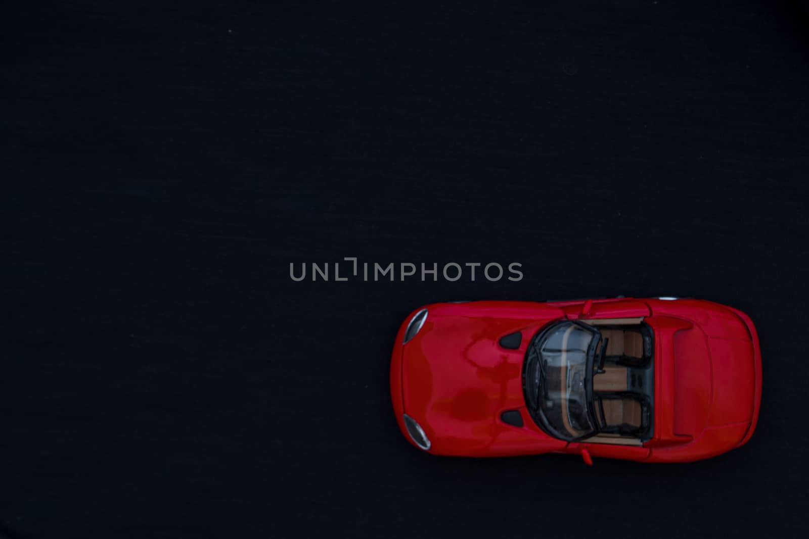 Flat lay of a red toy car with black background