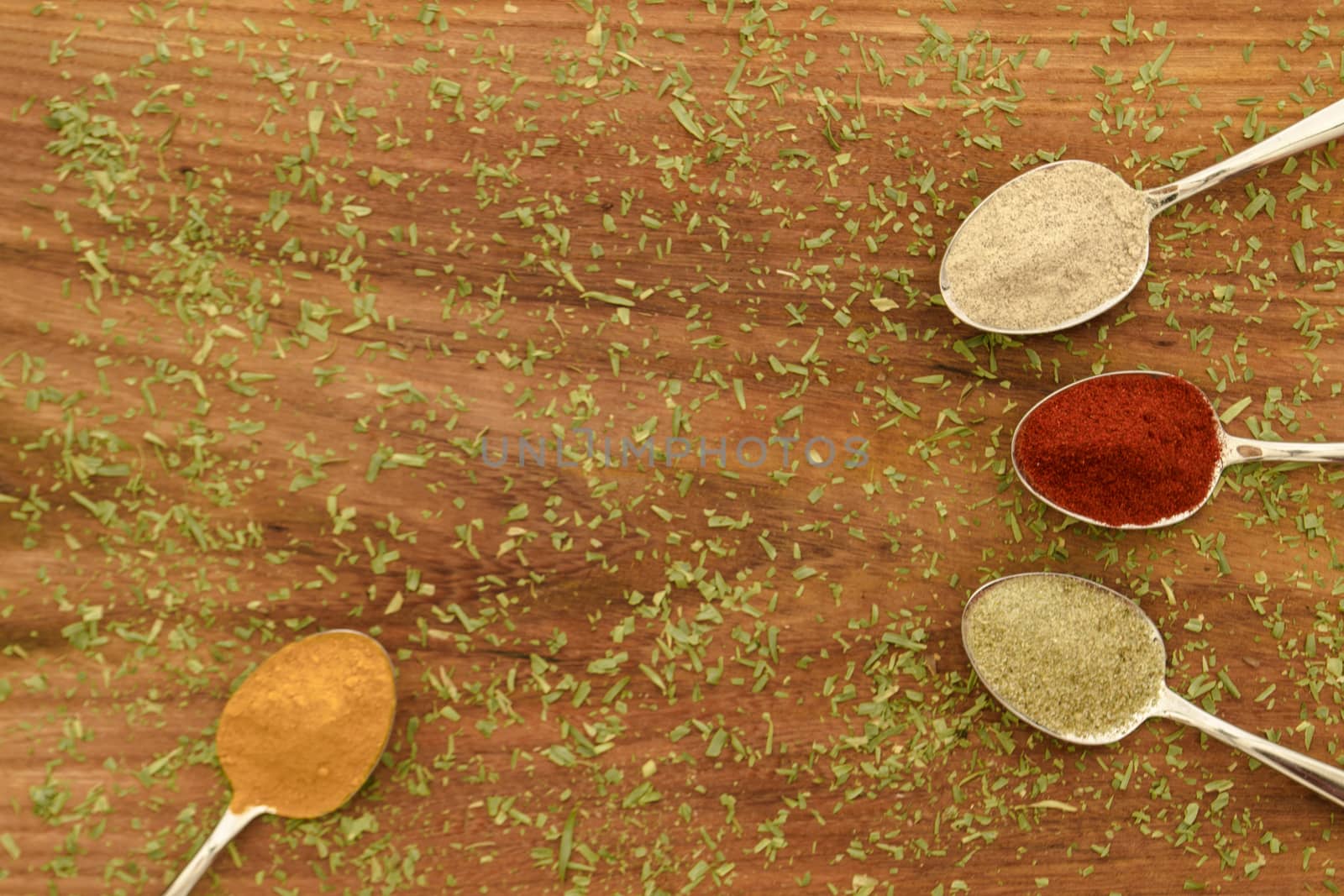 Various colorful spices arranged on spoons  with wooden background