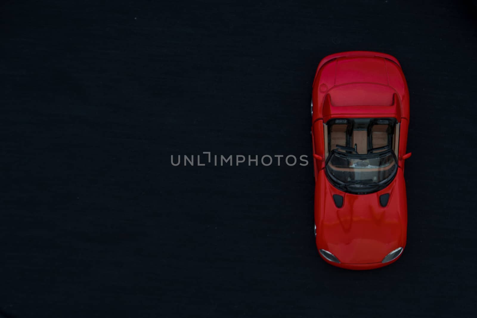 Flat lay of a red toy car with black background