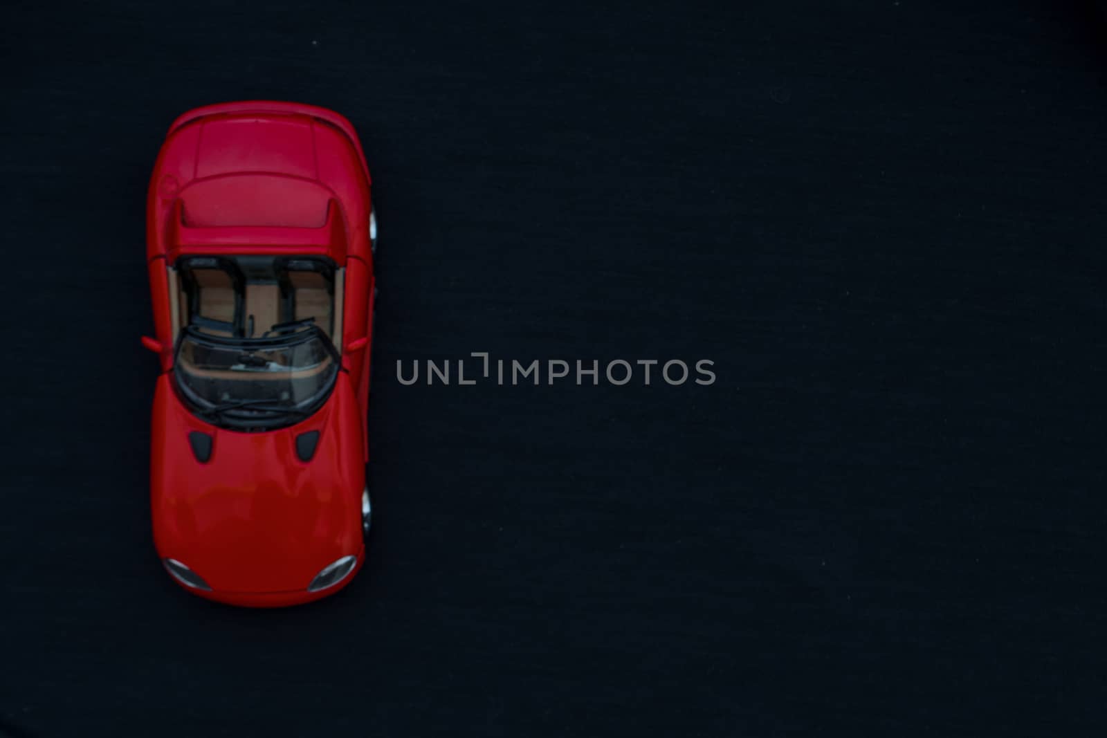 Flat lay of a red toy car with black background