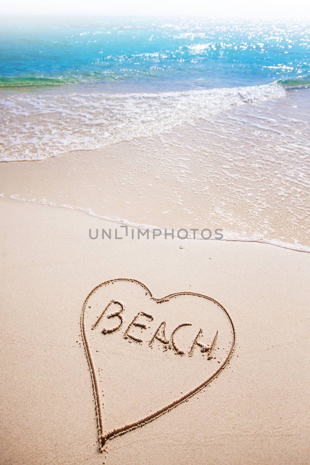 Heart drawing and word BEACH written on the sand of a beach