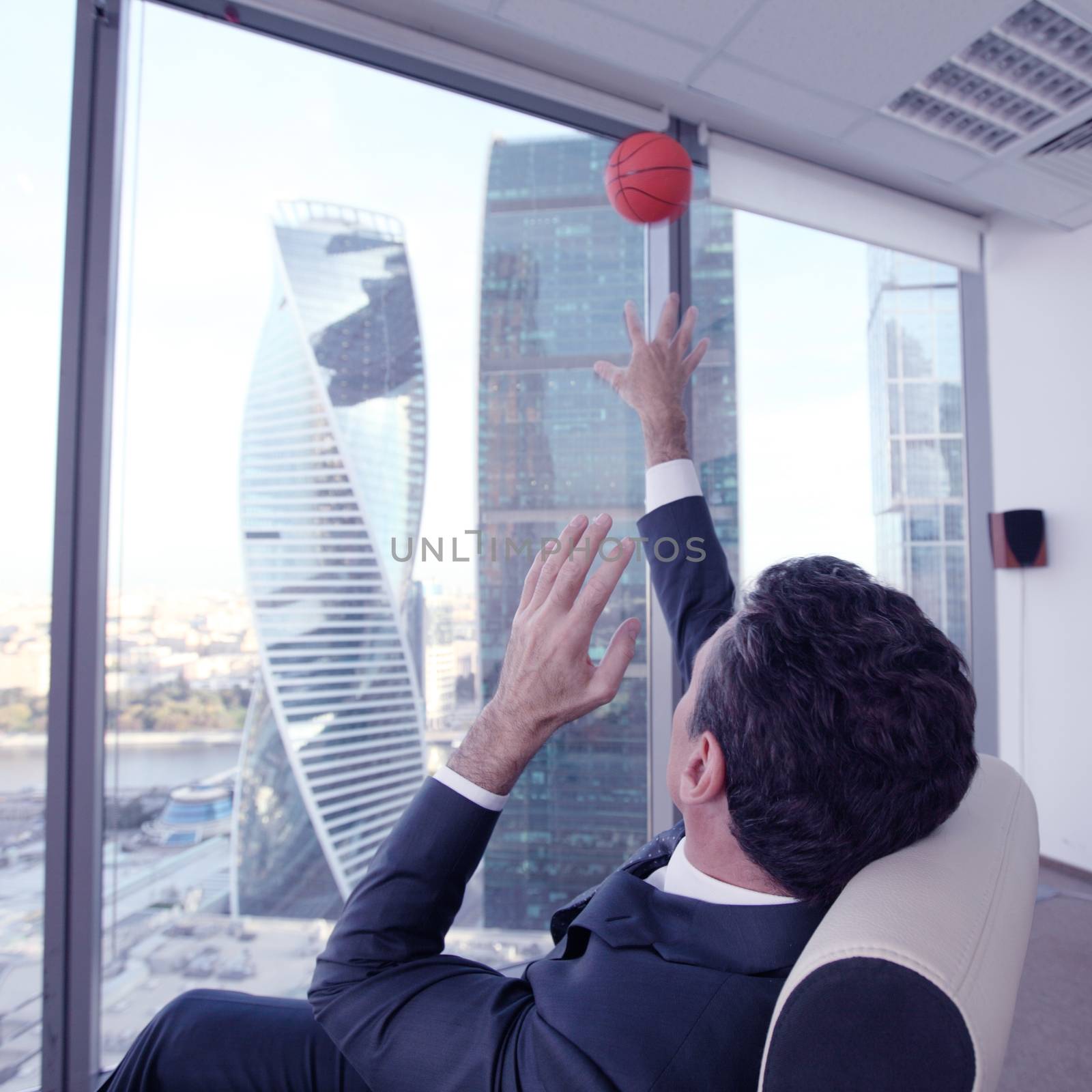 Business man playing with a basketball at the office