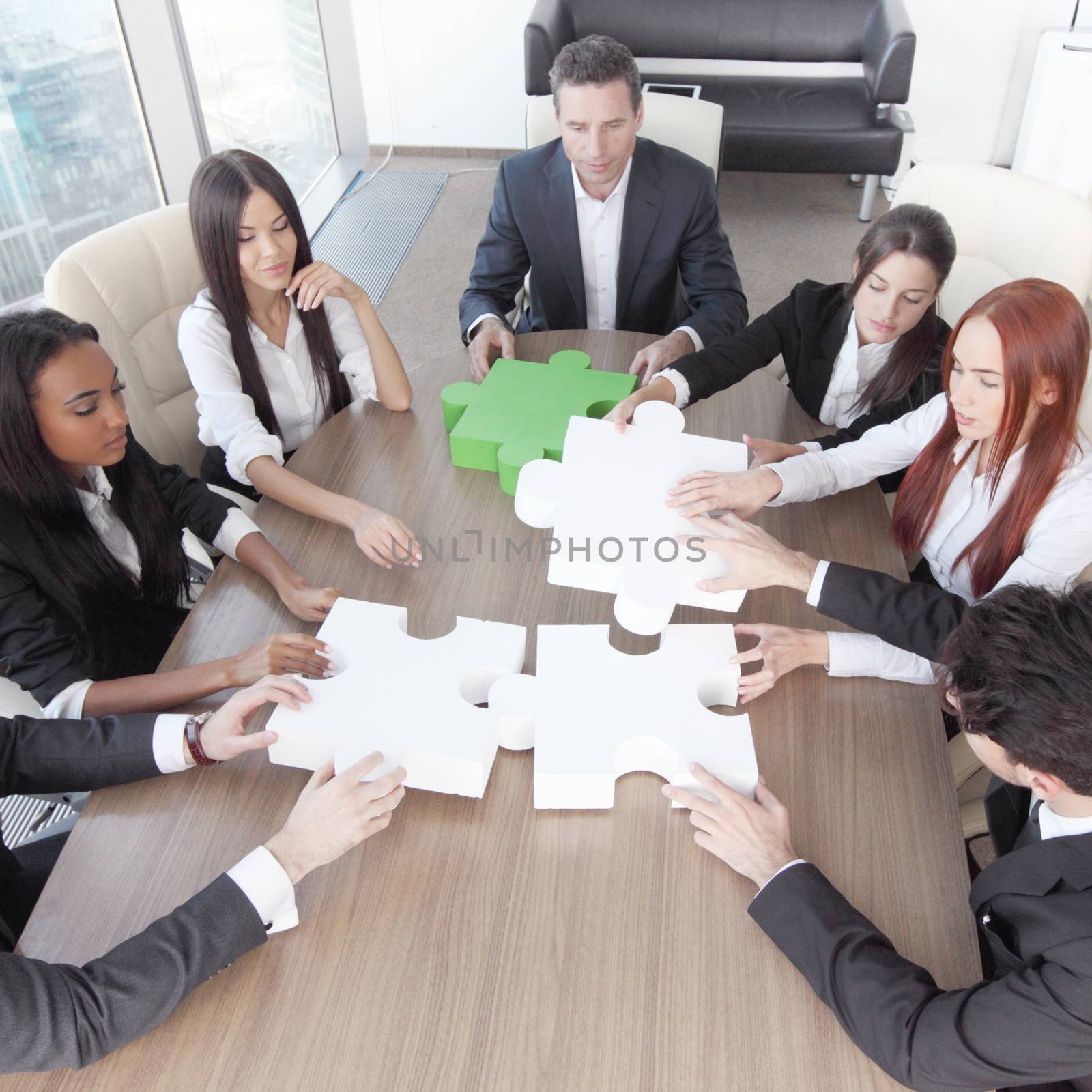 Group of business people assembling jigsaw puzzle and represent team support and help concept in office