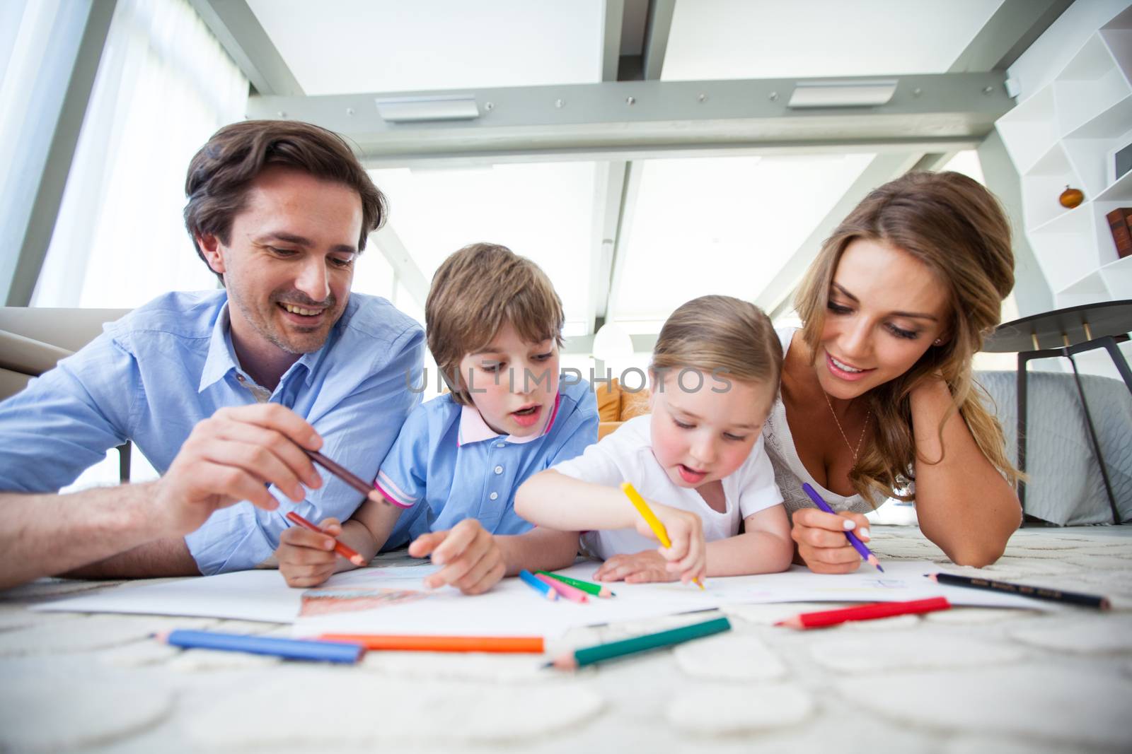 Charming family with children drawing together on the floor in a living room