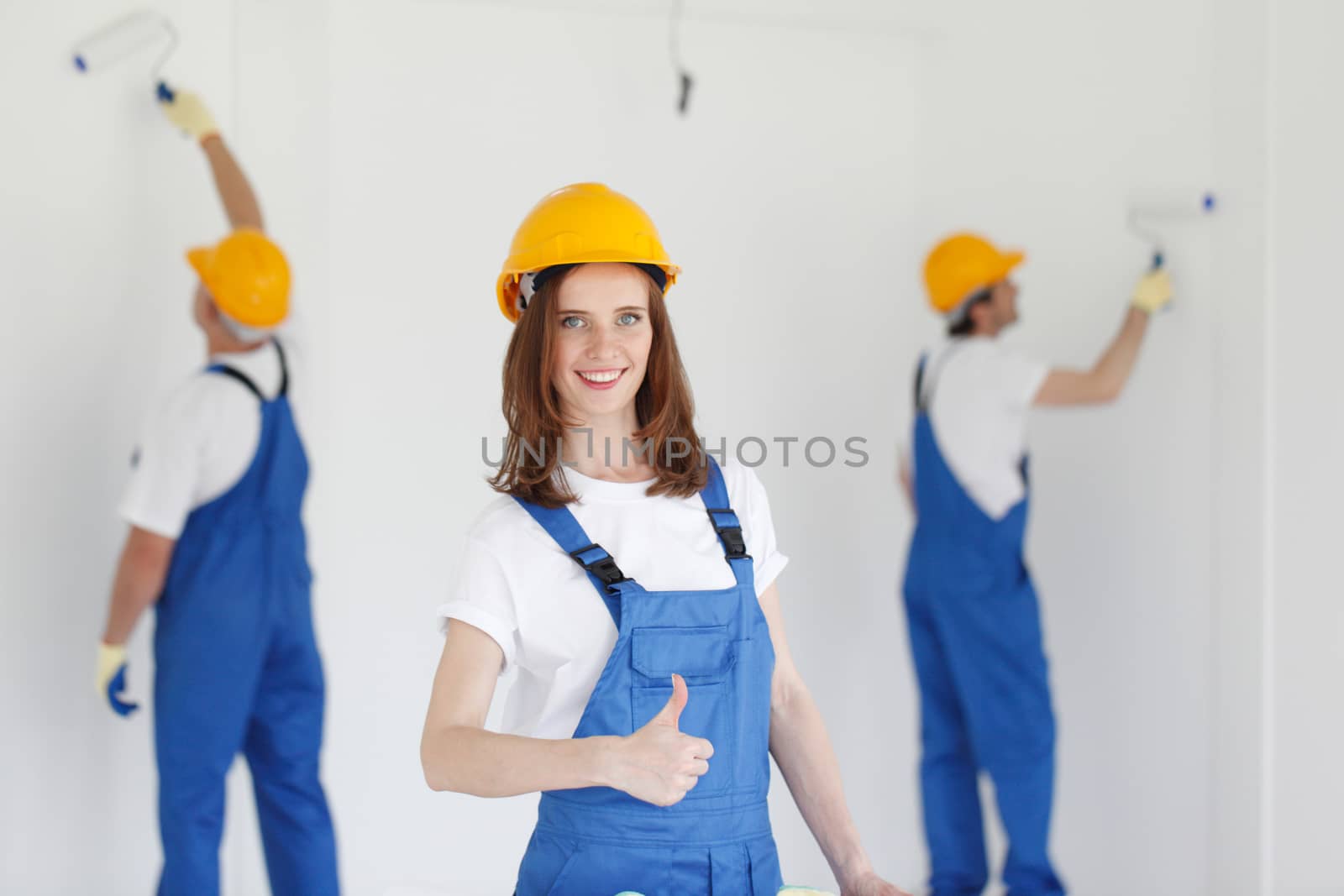 Two young workers in uniform painting the wall