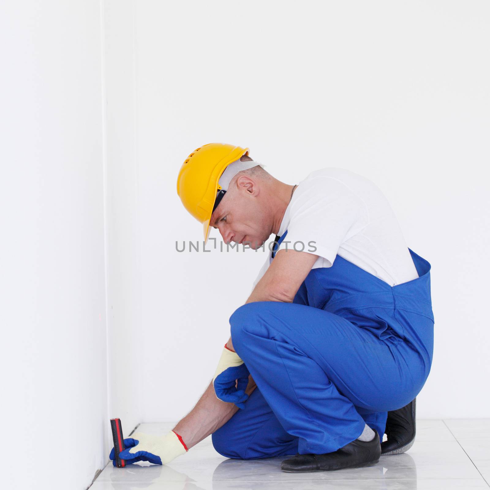 The worker makes finishing works of walls using laser line level. Laser roulette device