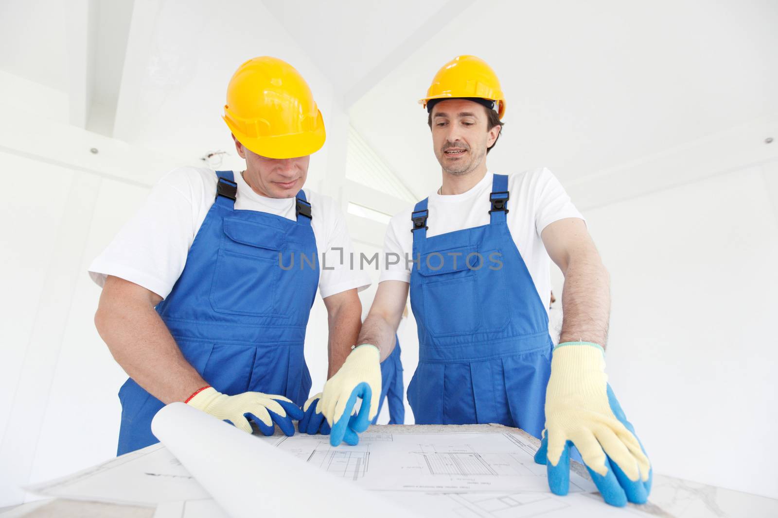 Construction workers with blueprint by ALotOfPeople