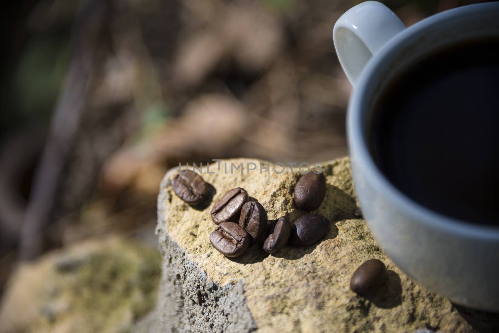 Cup of coffee and coffee beans on a stone background.
