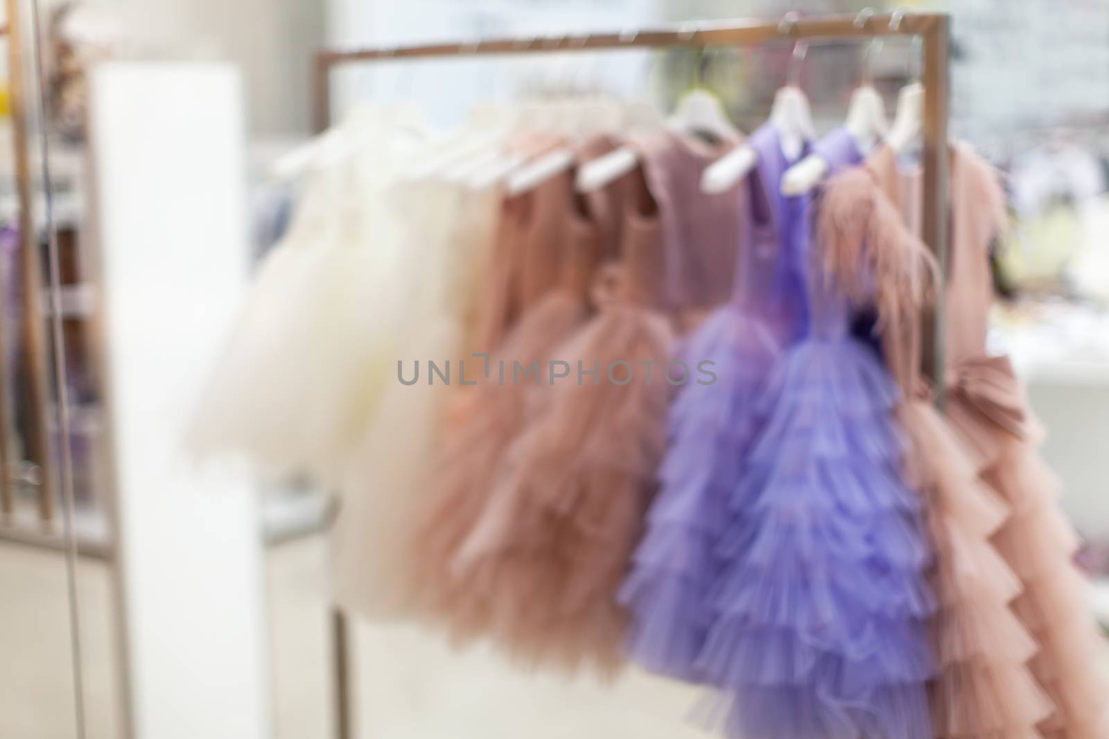 Showcase in store in defocus. Blurred view of beautiful ball gowns that hang on hangers. Concept shopping, discounts, sales, black friday, cyber monday. Fashion for girls.